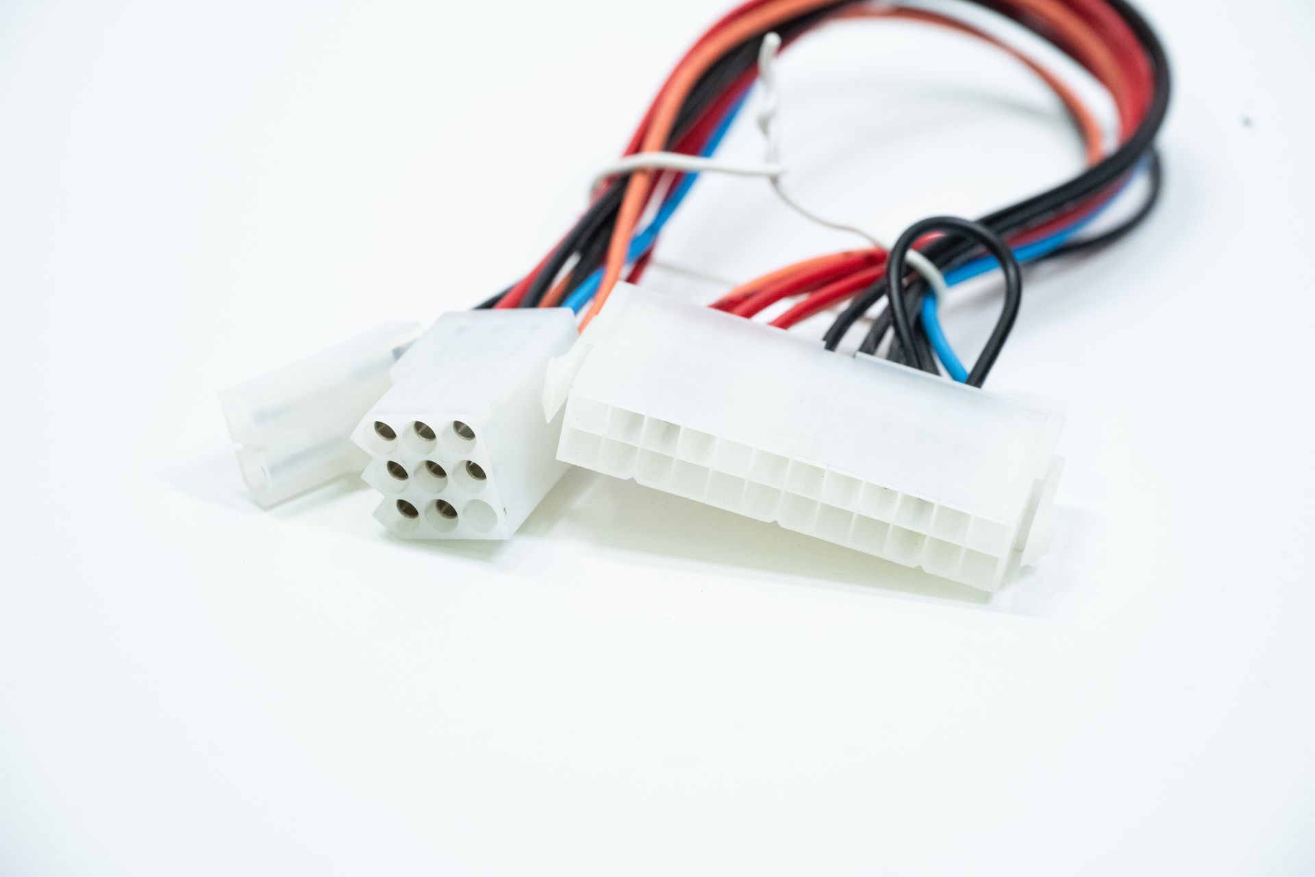 Close-up of white computer power supply connectors with various colored wires against a white background.