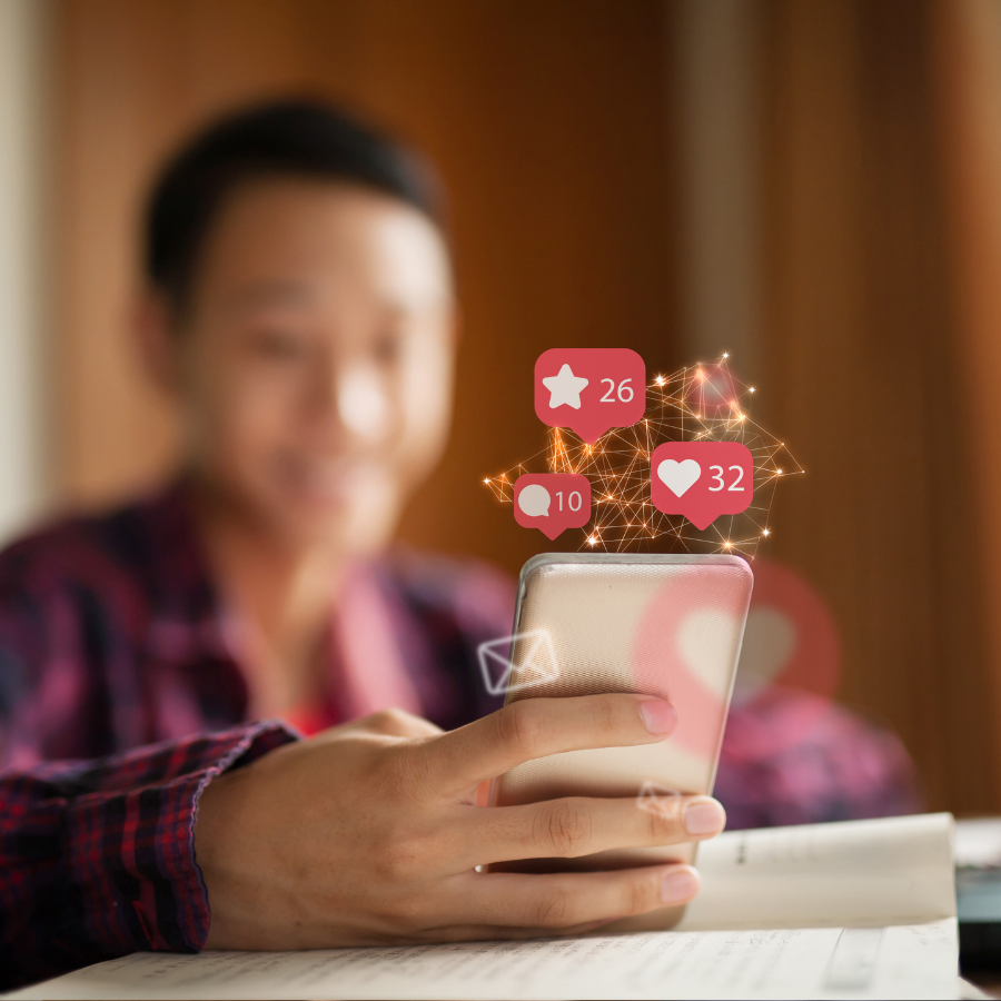 Person using a smartphone with social media notification icons floating above it