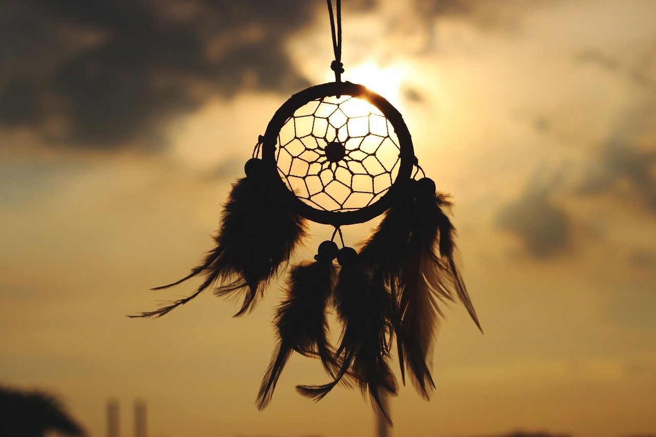 Photo of a dream catcher, taken in front of a yellowish sunset