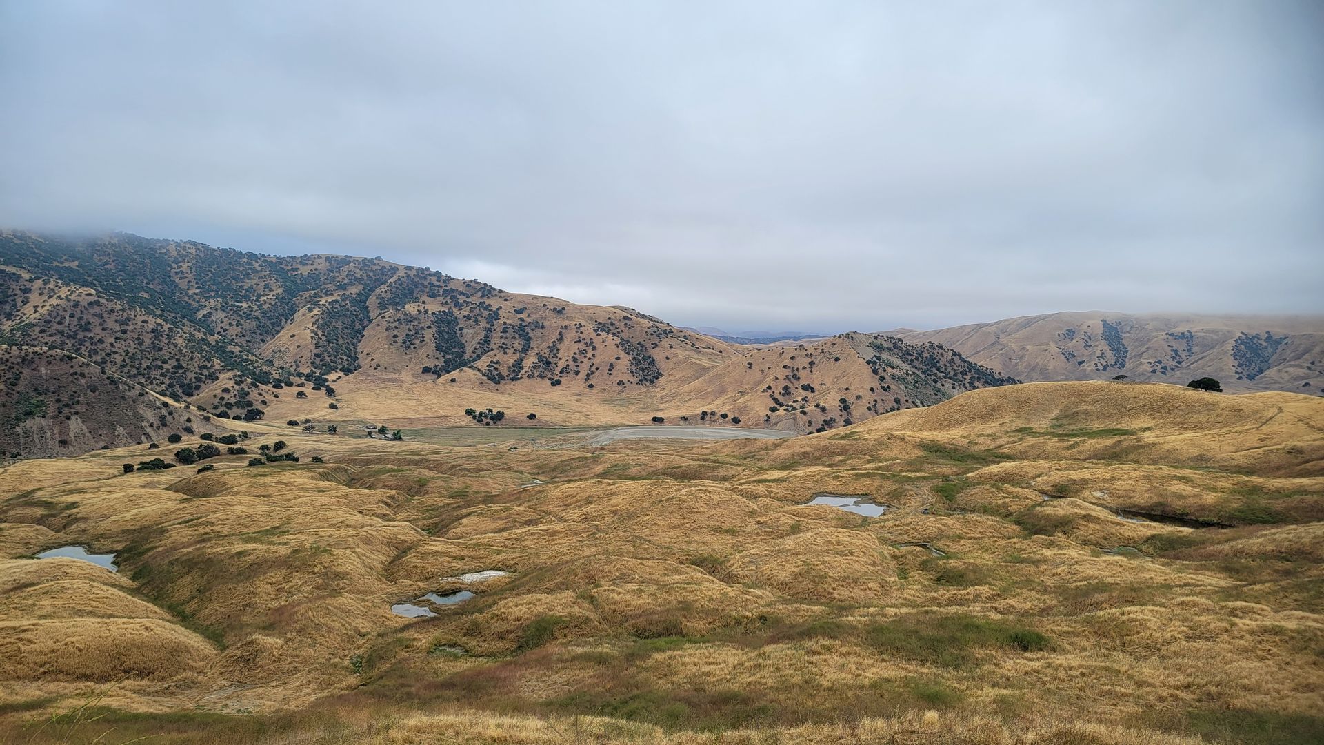 Rocky hills and grassy plains under a cloudy sky in a wide mountain landscape