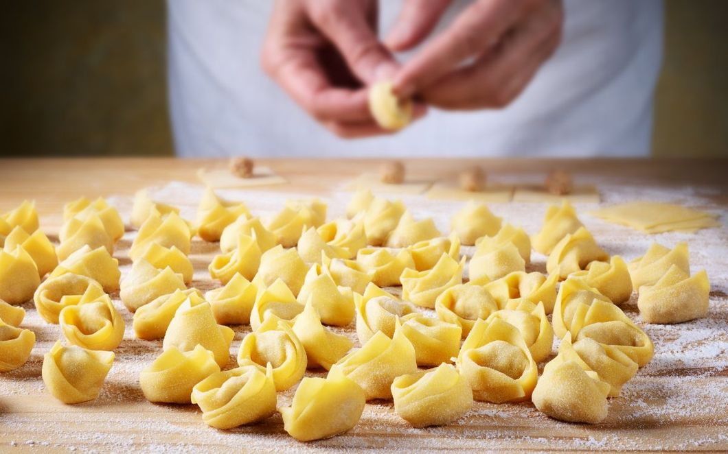 Tortellini freschi crudi sparsi su un tagliere di legno infarinato