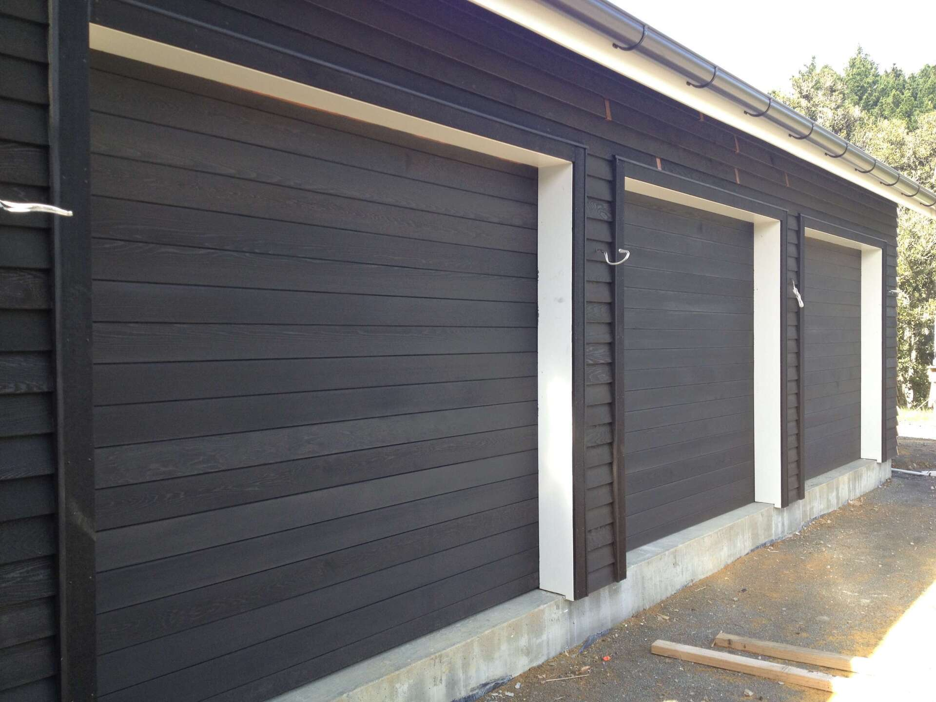 A row of black garage doors with white trim