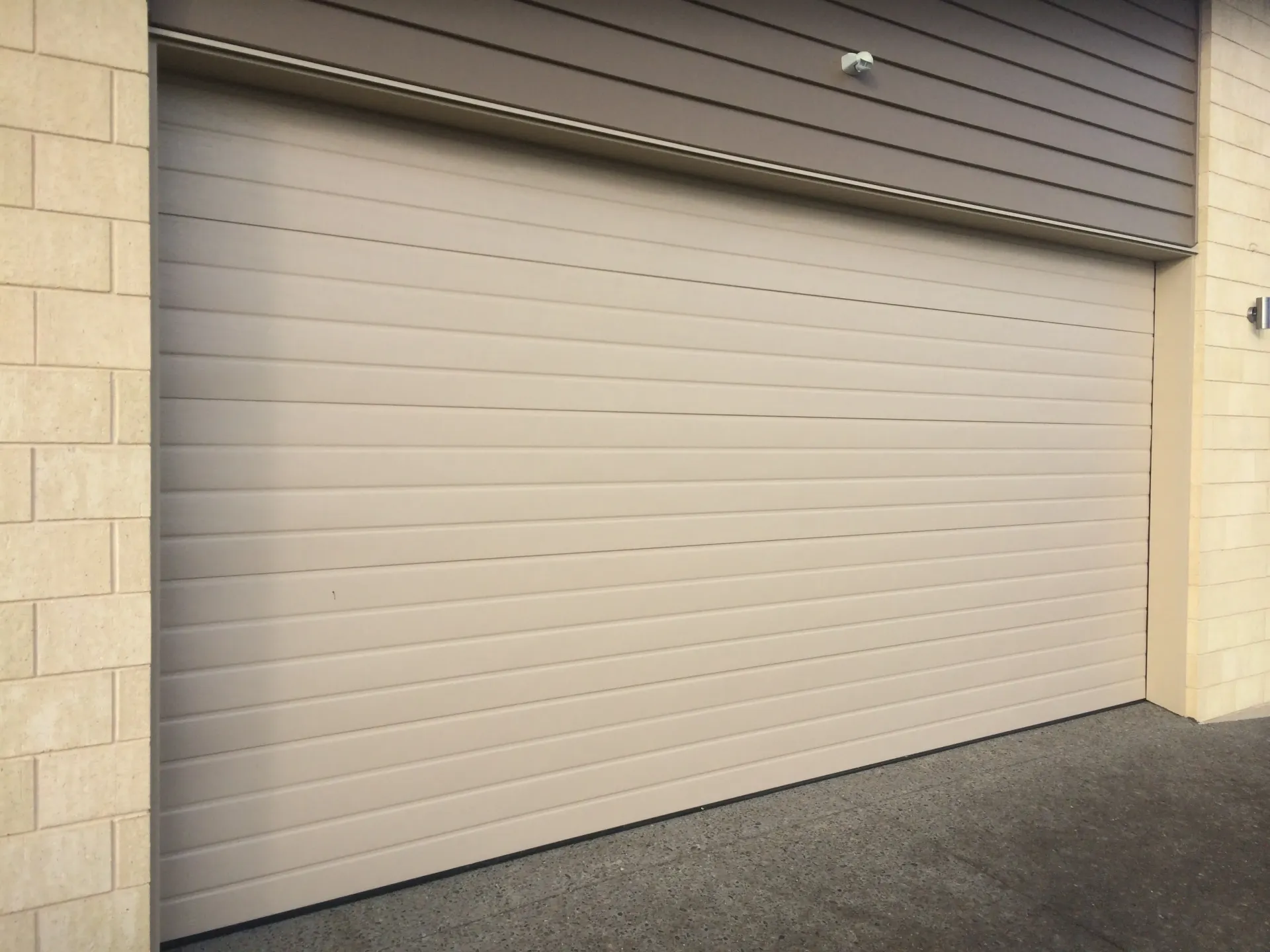 A white garage door is open on a brick building