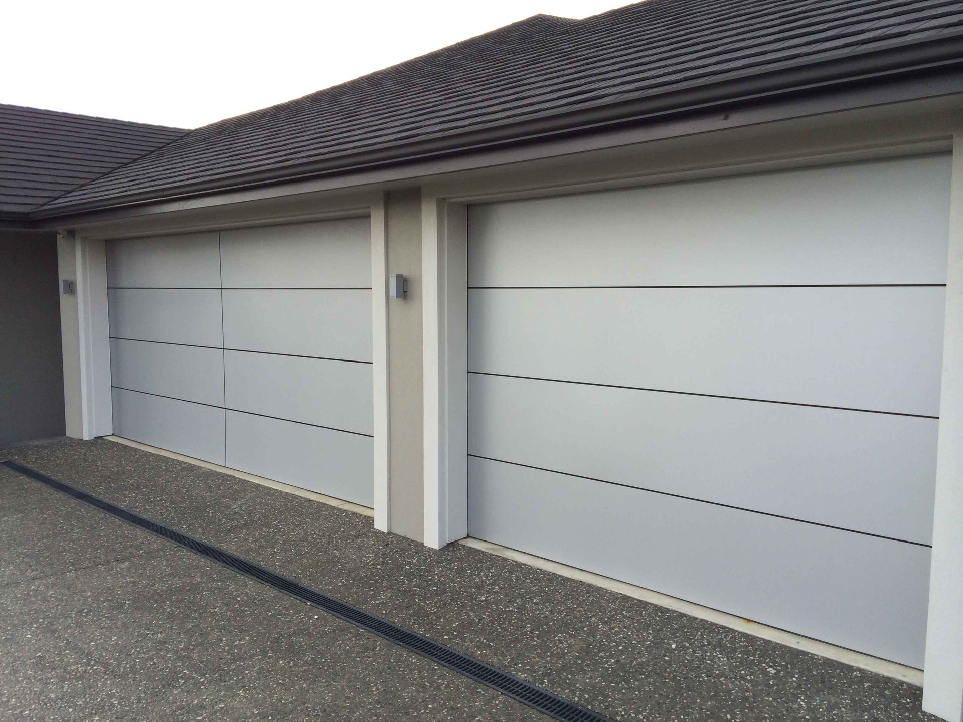 A row of white garage doors on the side of a house