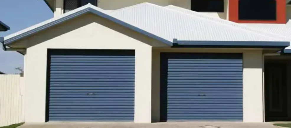 A white house with two blue garage doors and a white roof.