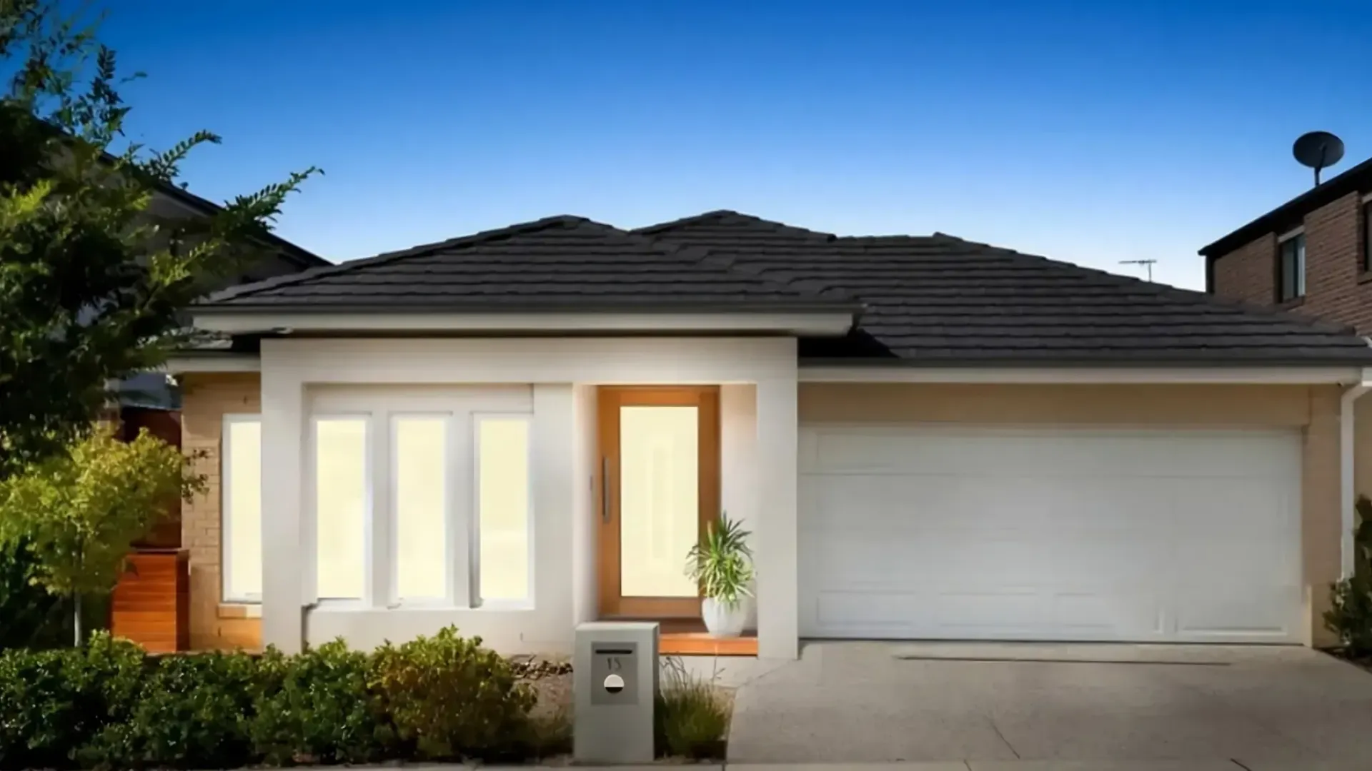 A white house with a black roof and a white garage door