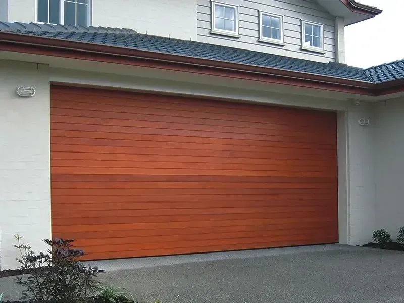 A white garage door is sitting in front of a house.