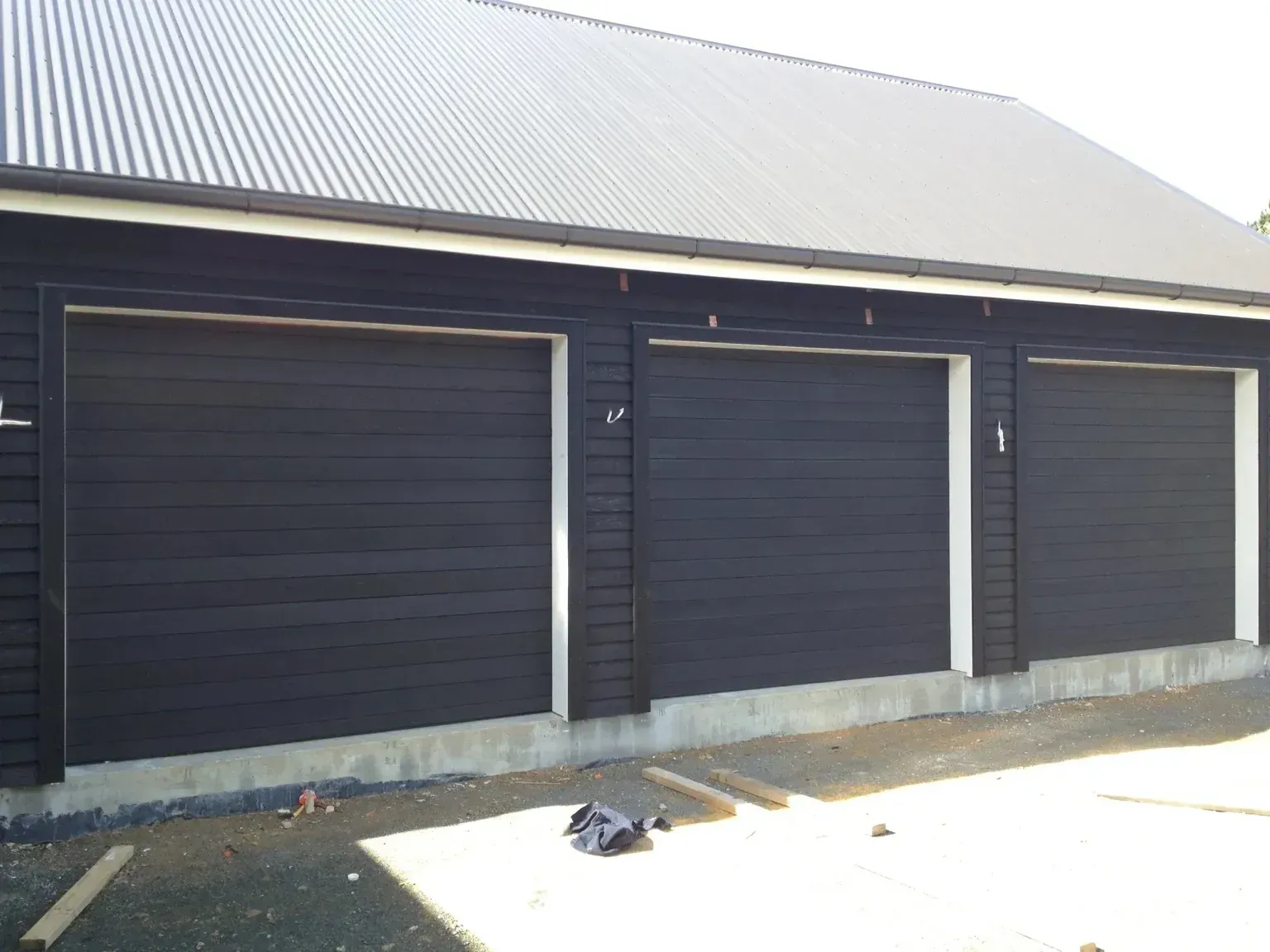 A black garage with three doors and a white trim