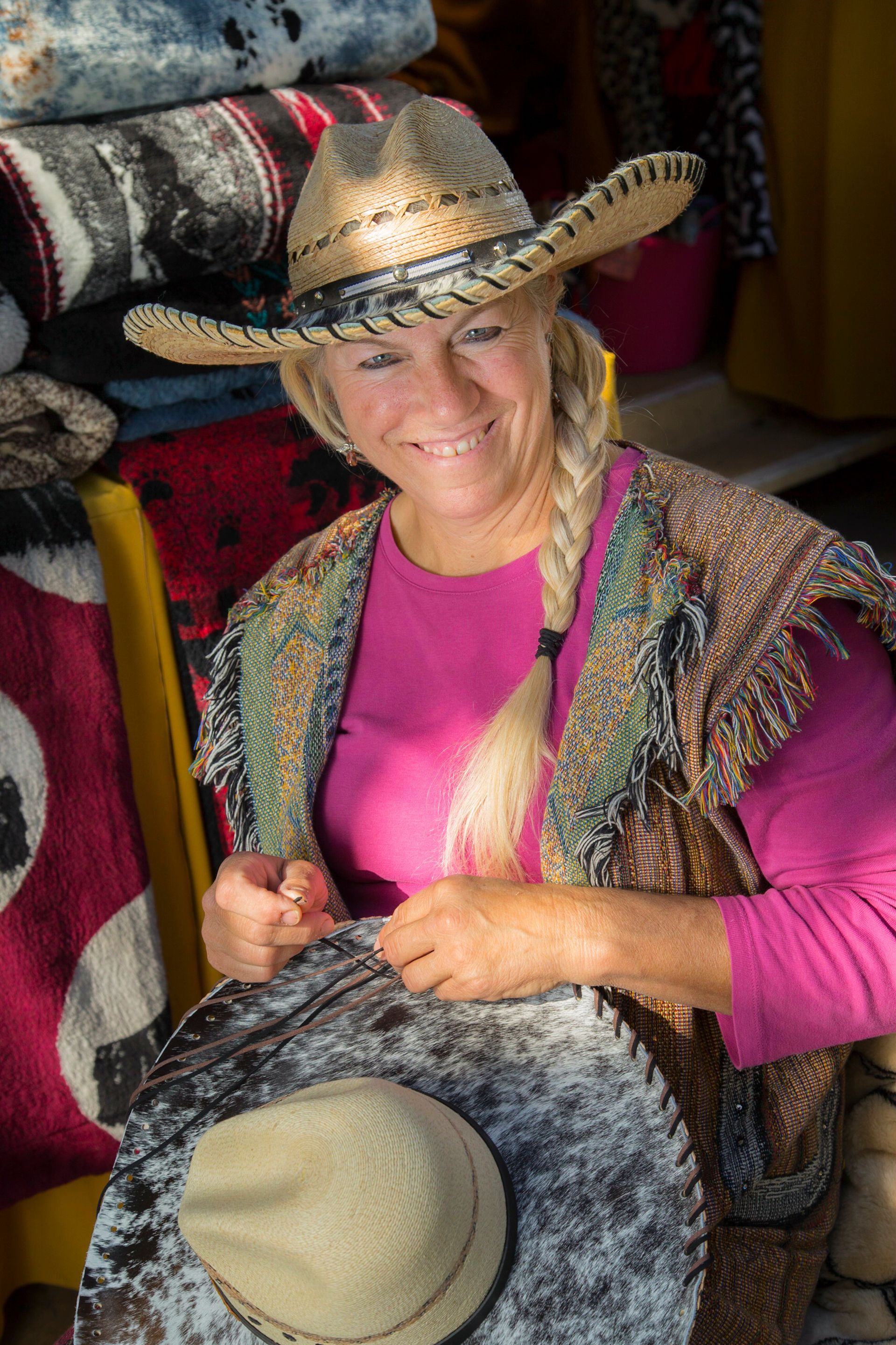 A woman wearing a cowboy hat is holding a sombrero and smiling.