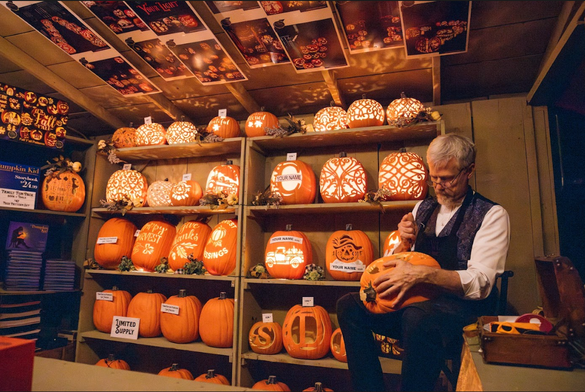A man is carving a pumpkin in a store filled with pumpkins