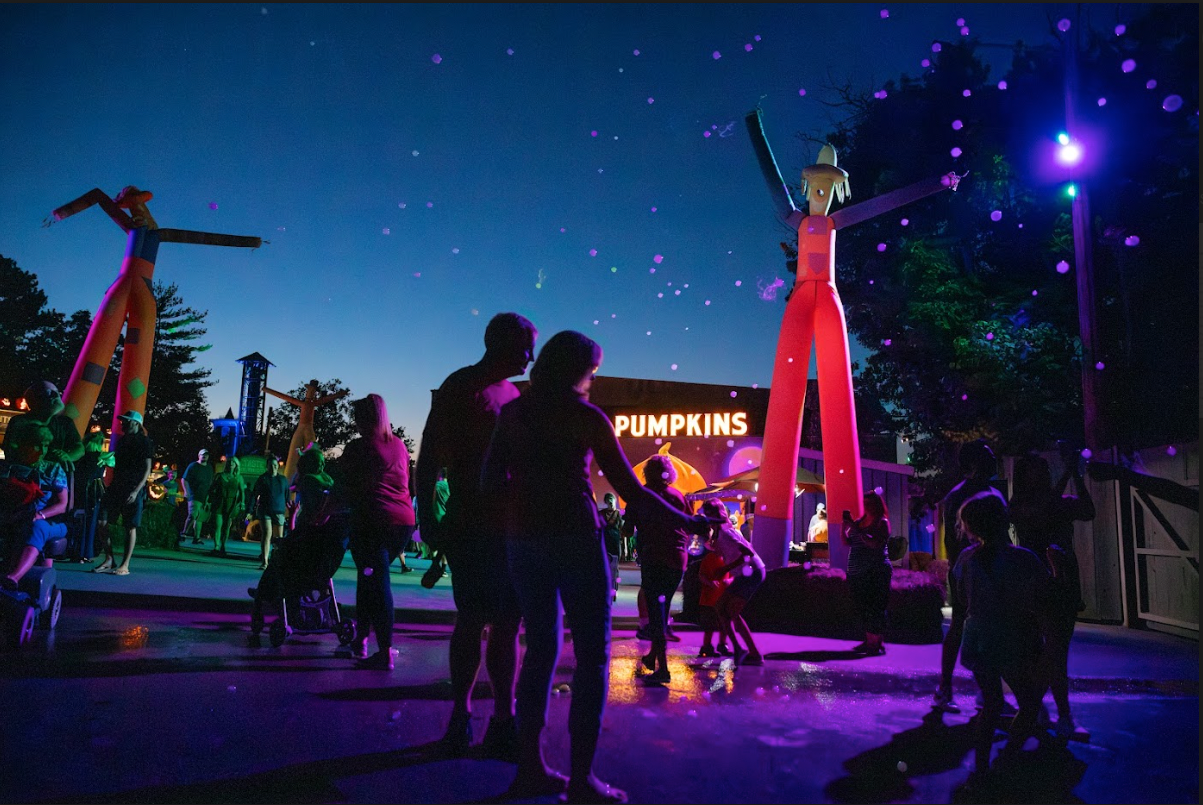 A group of people are standing in front of a building that says pumpkins.