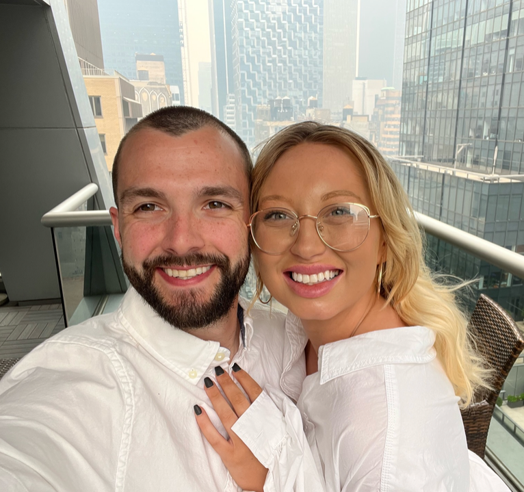 A man and a woman are posing for a picture on a balcony.