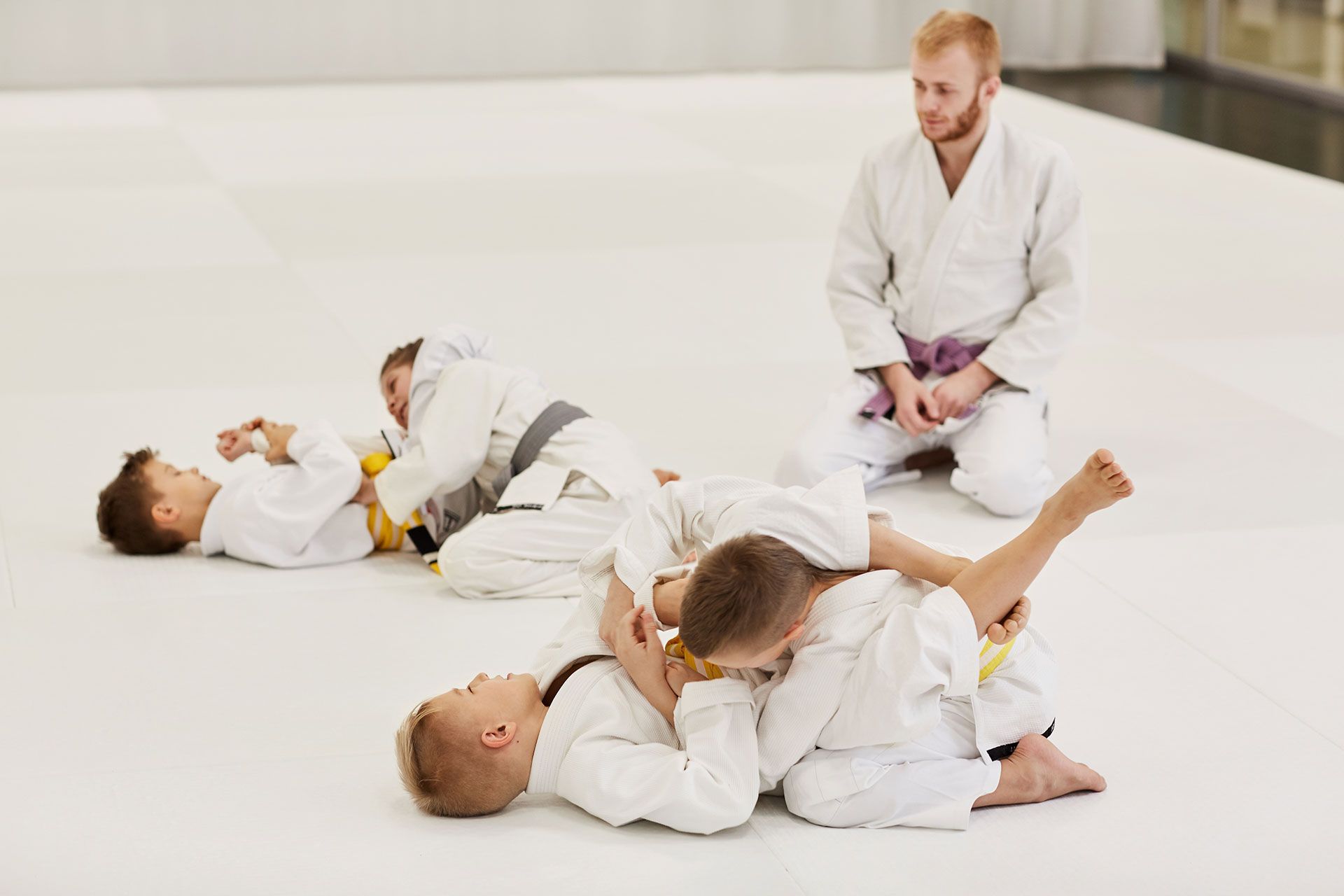 A group of young boys are practicing jiu jitsu with a coach.