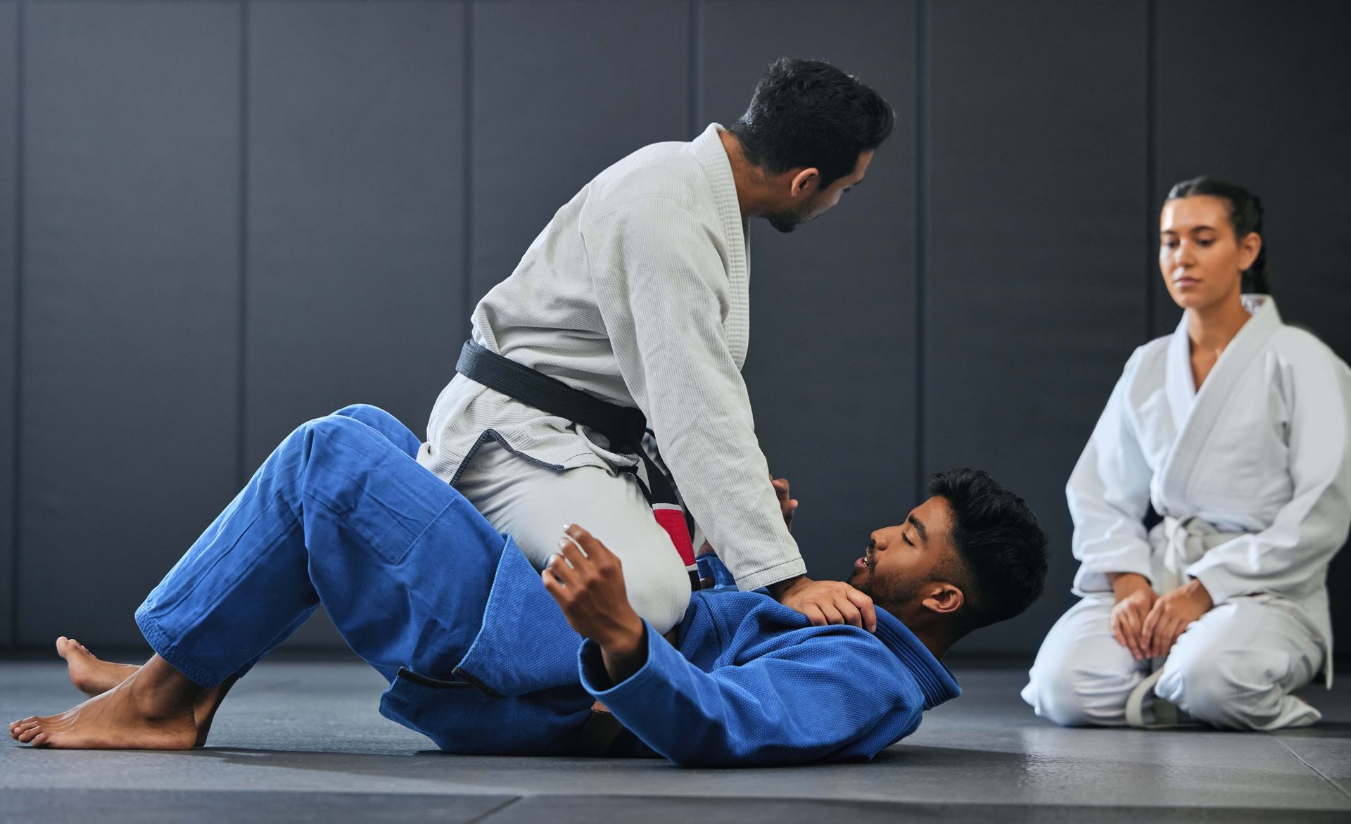 A group of people are practicing judo in a gym.