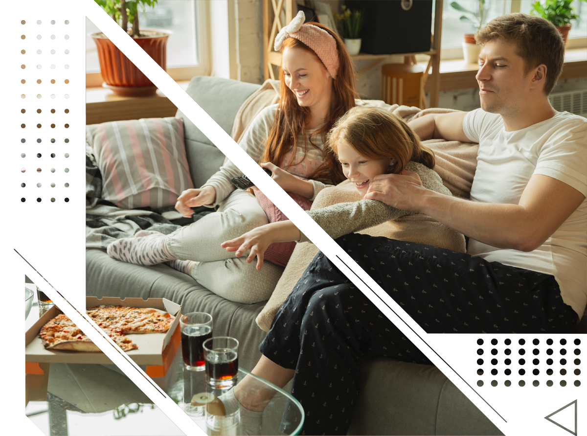 A family is sitting on a couch watching tv.