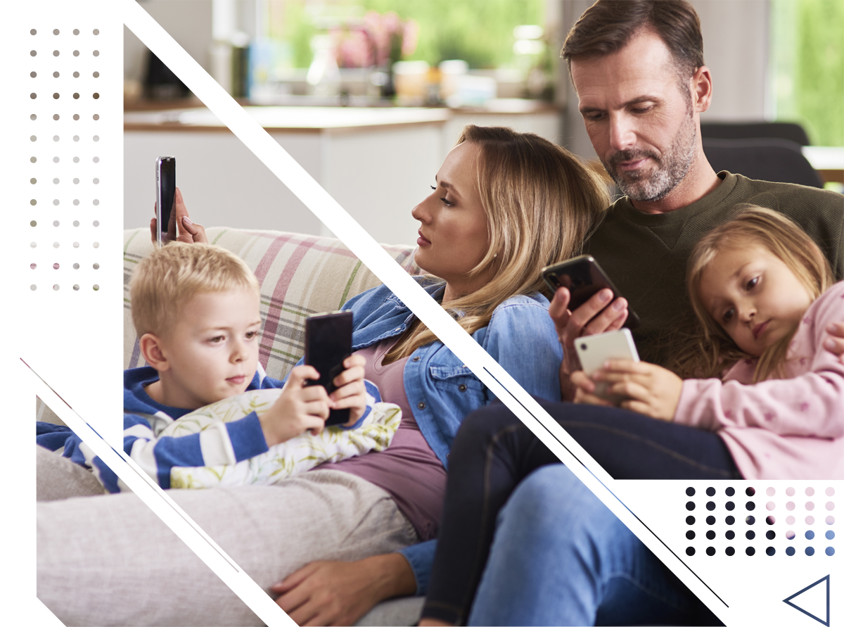 A family is sitting on a couch looking at their phones.