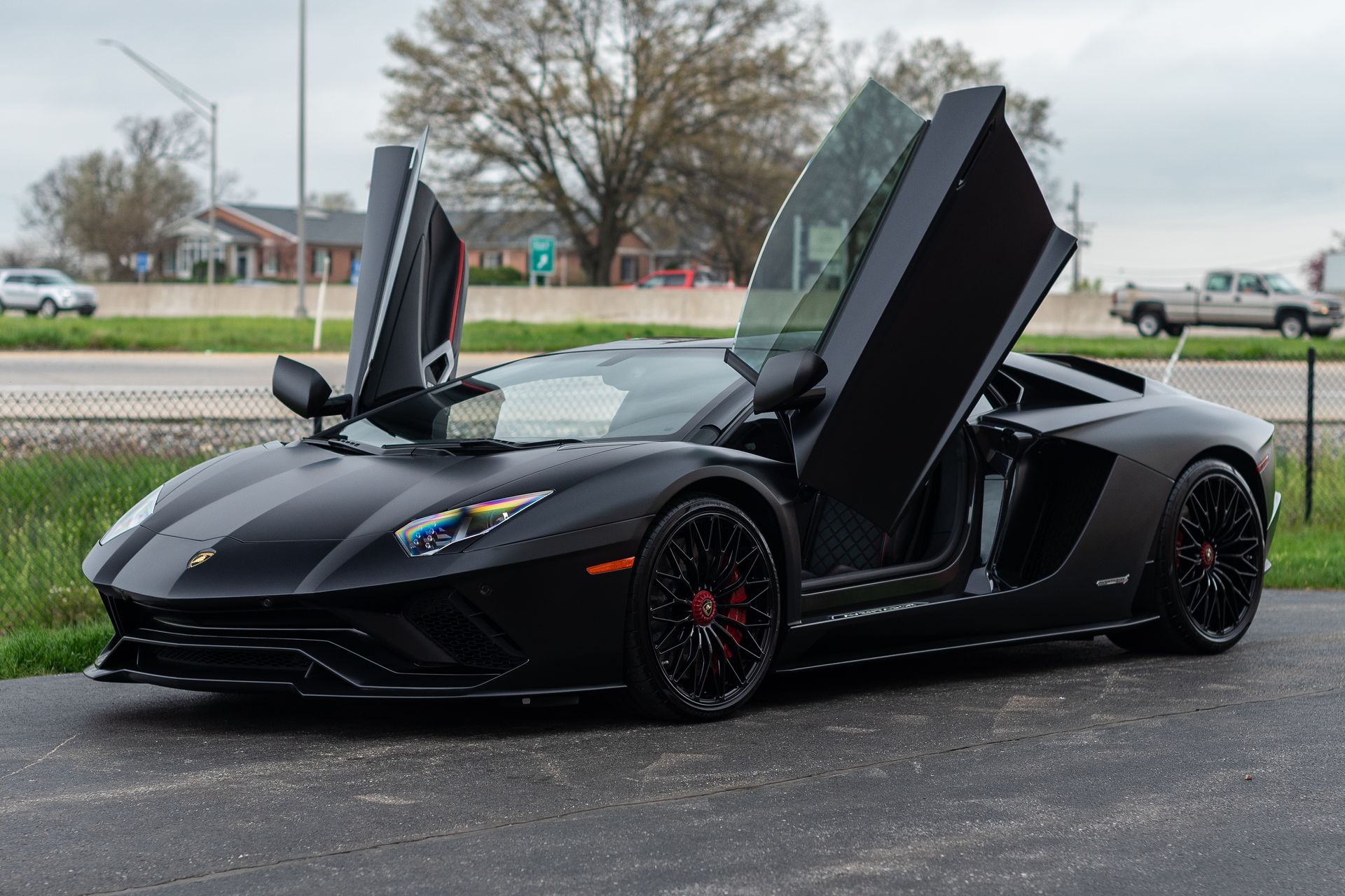 Black Lamborghini Aventador with doors open parked on asphalt.