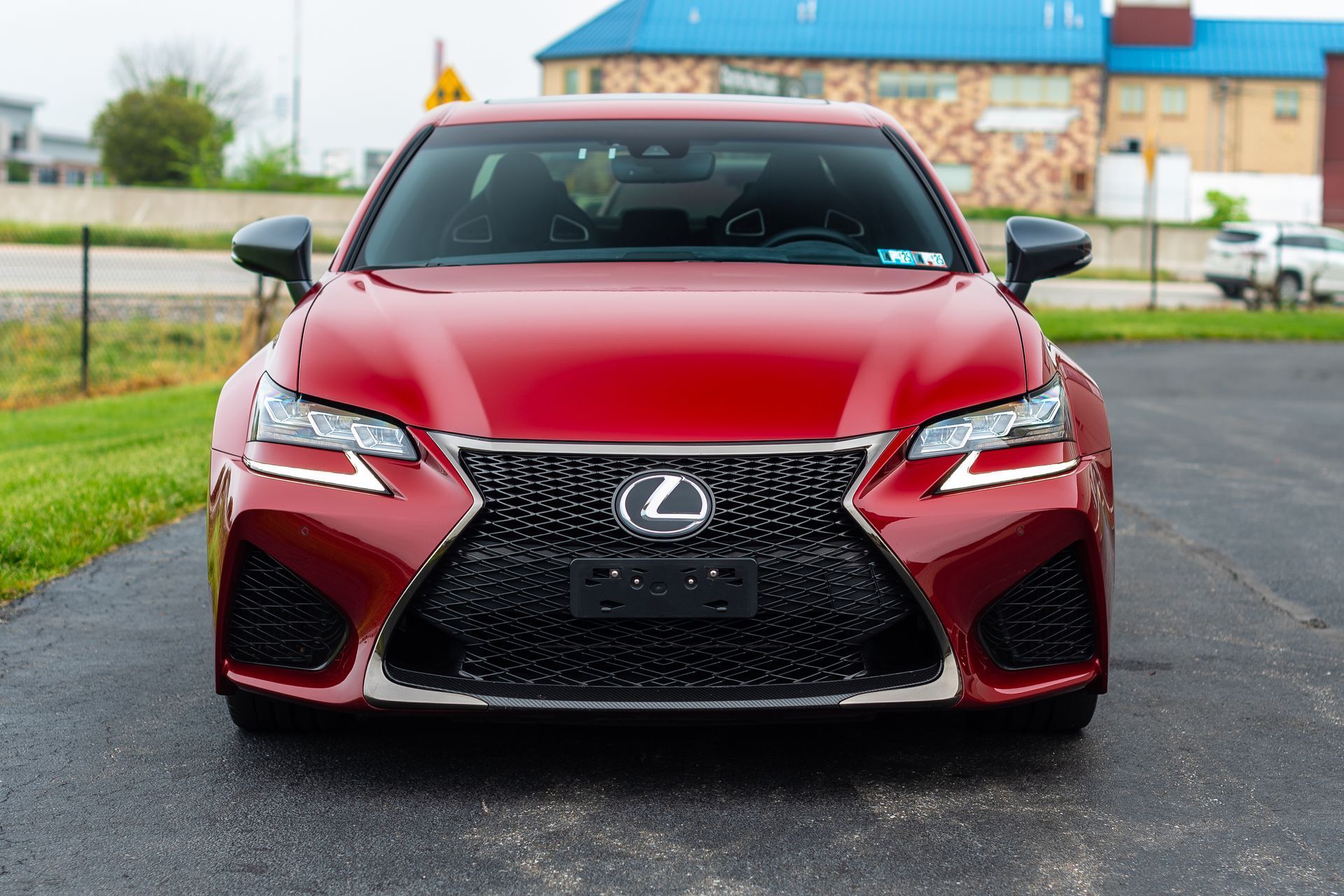 A red lexus is parked in a parking lot.
