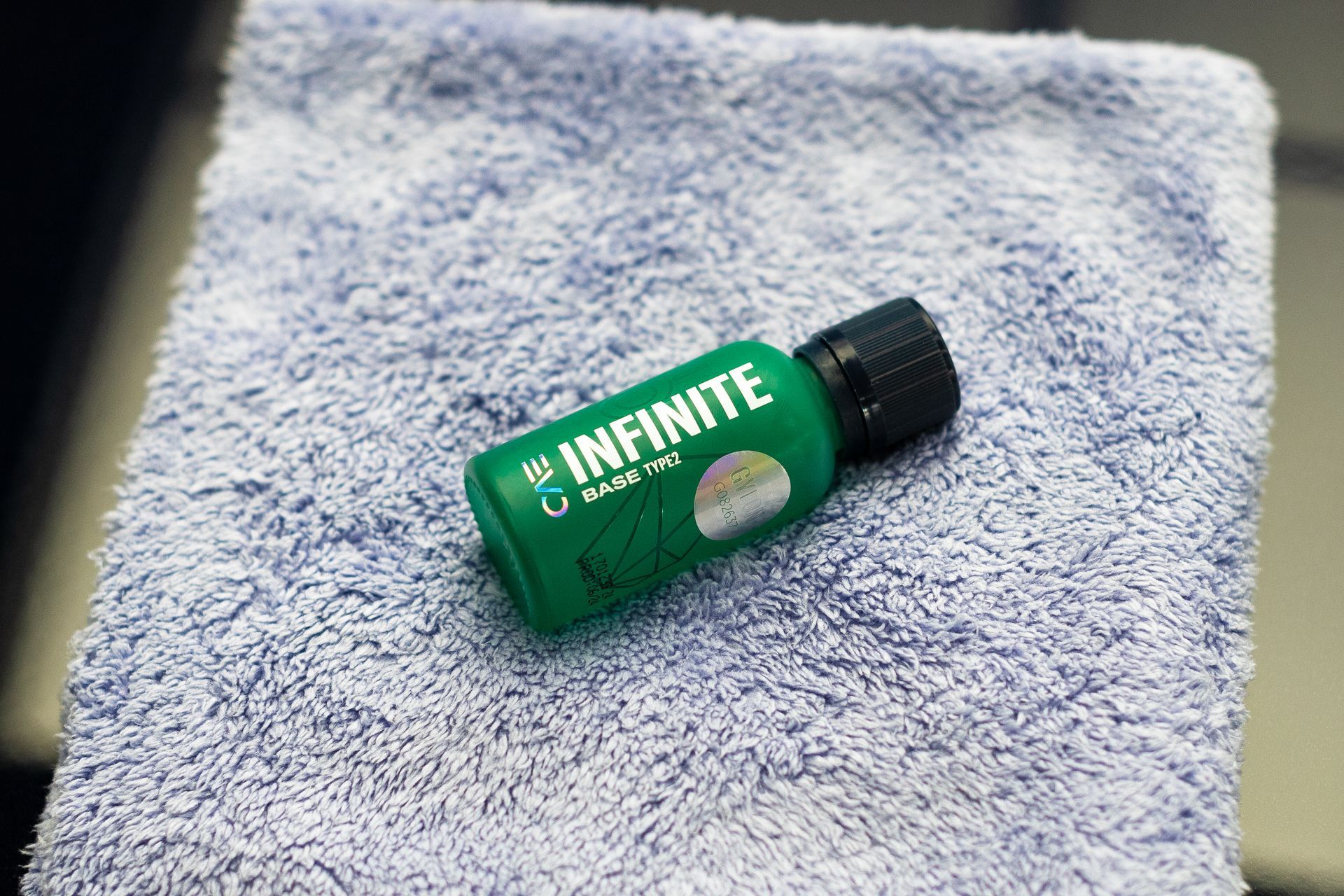 A green bottle is sitting on top of a blue towel.