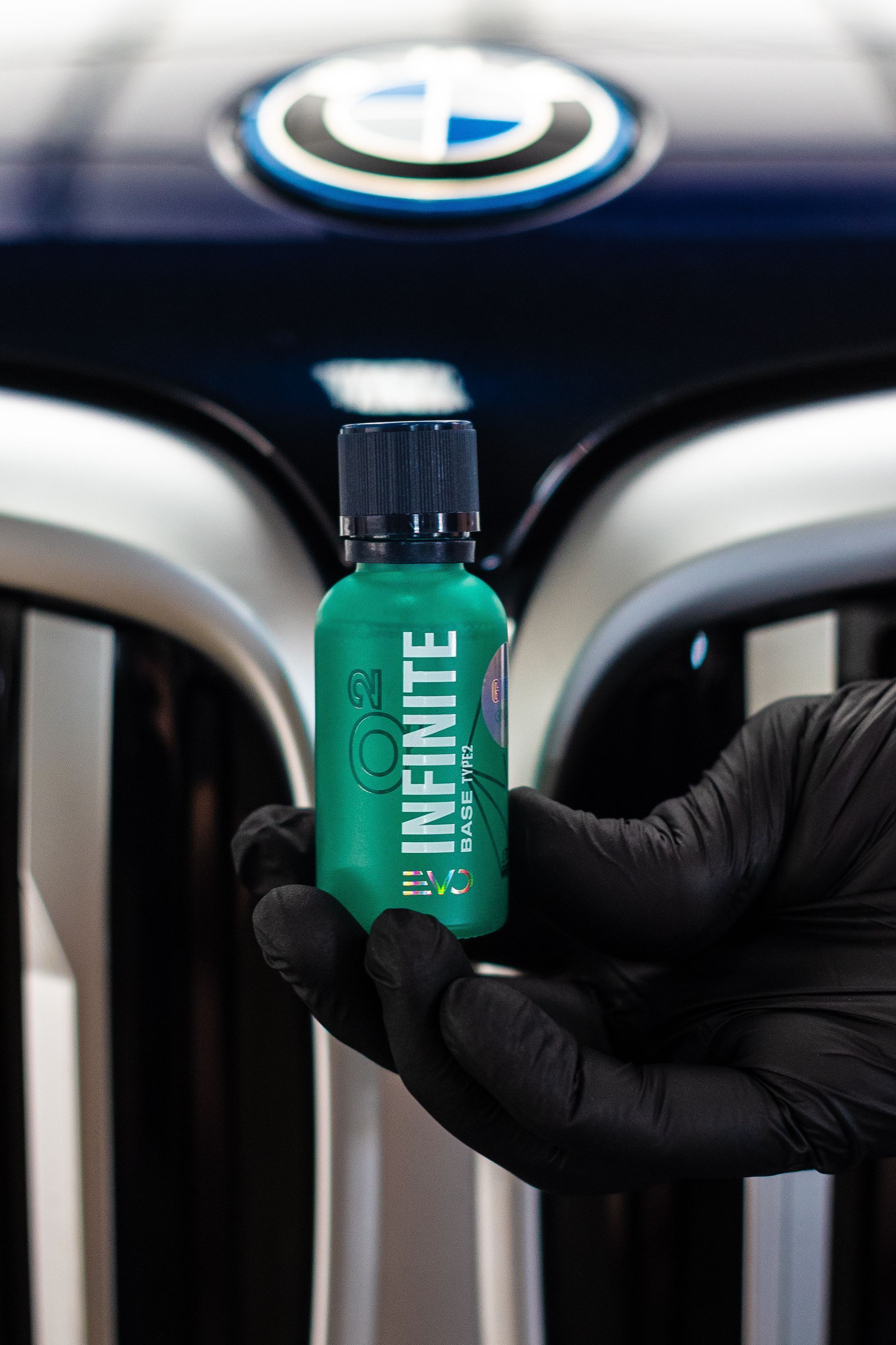 Black-gloved hand holding a green bottle of