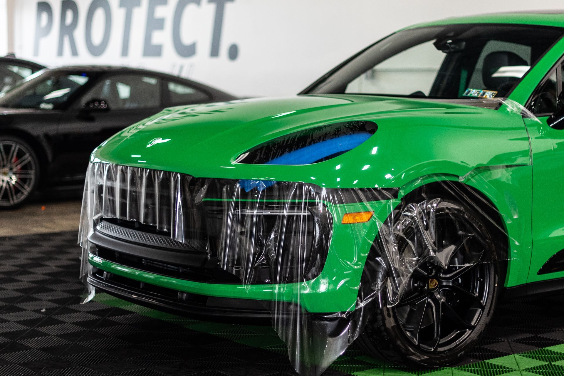 A green porsche macan turbo is covered in plastic wrap.