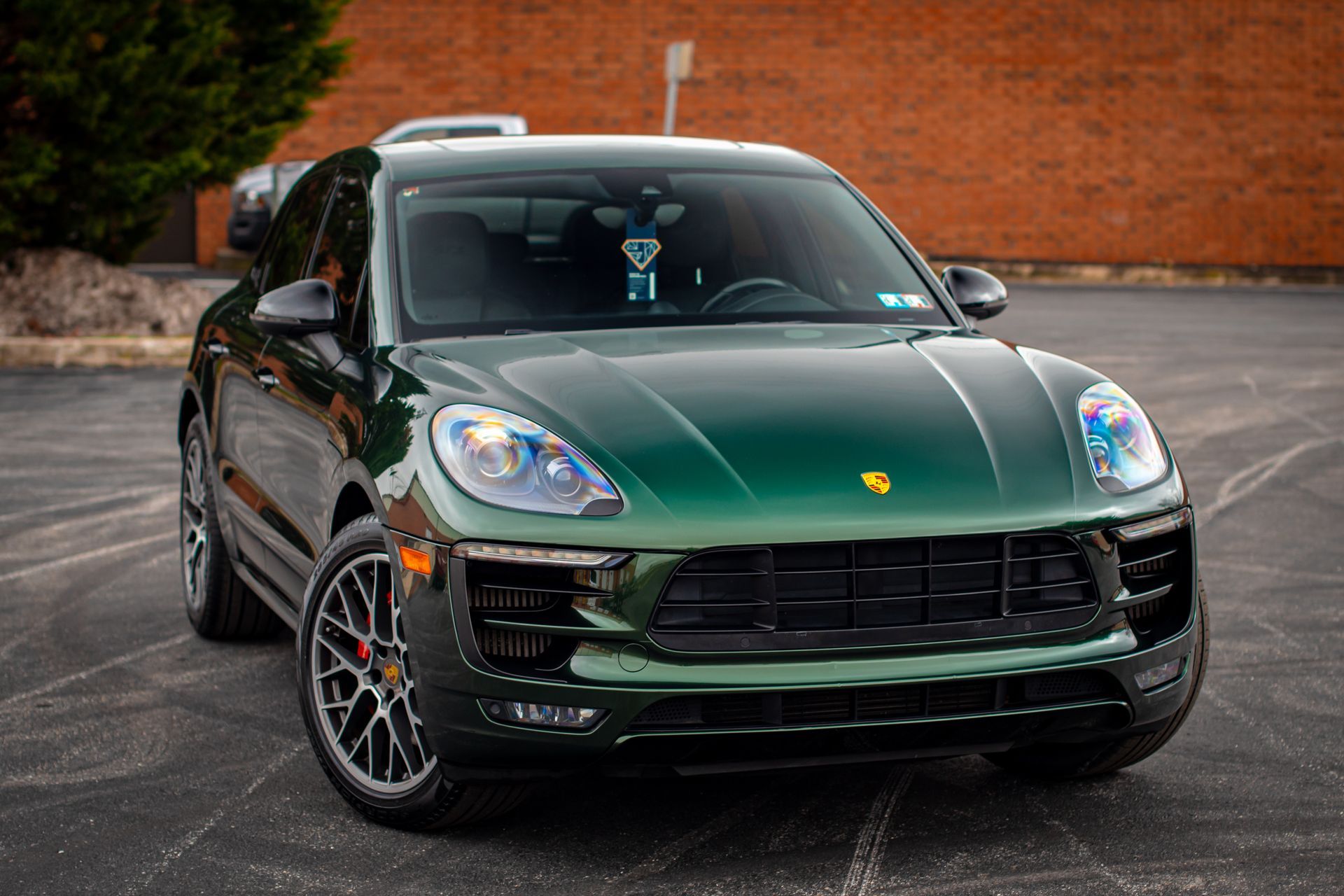 A green porsche macan turbo is parked in a parking lot.