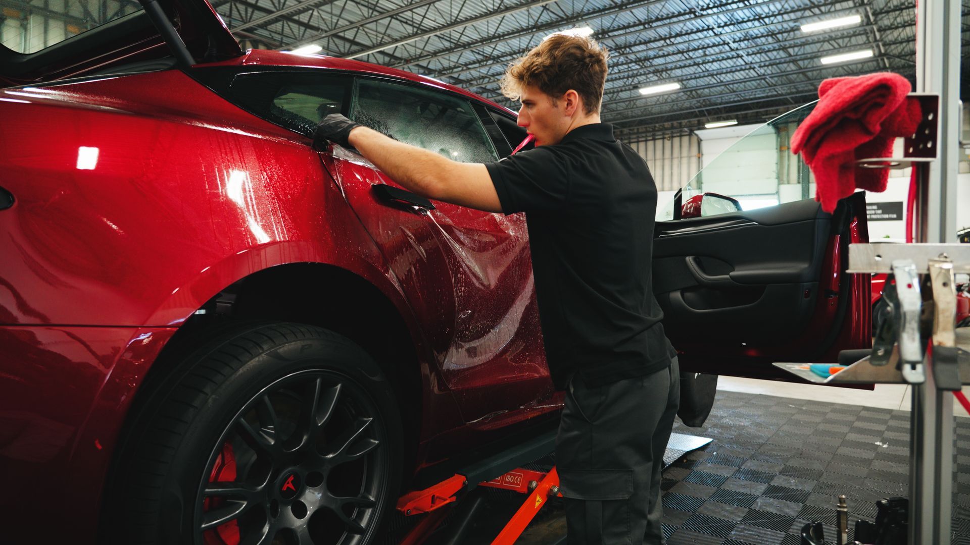 A man is working on a red car in a garage.
