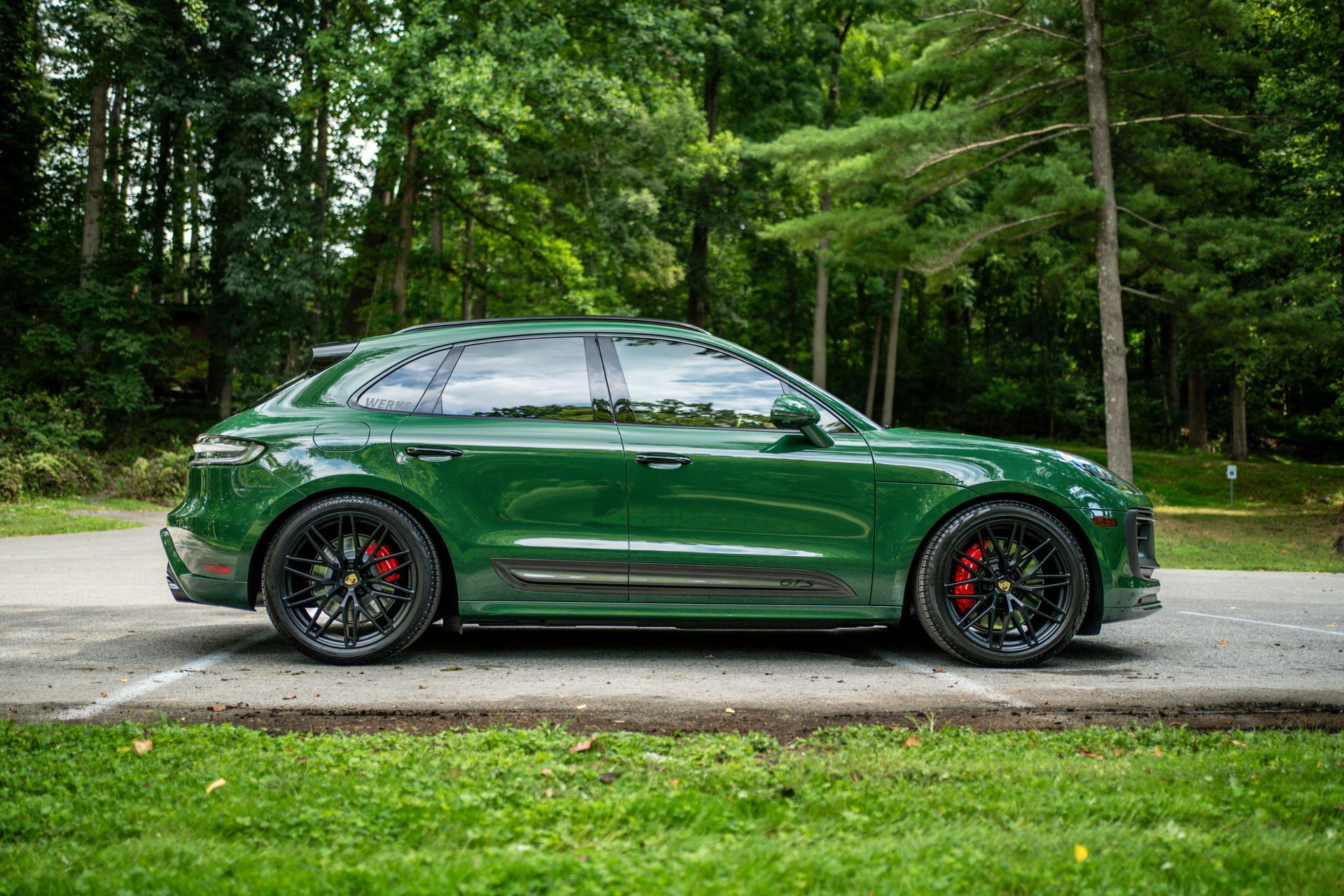 A green porsche macan turbo is parked on the side of the road.