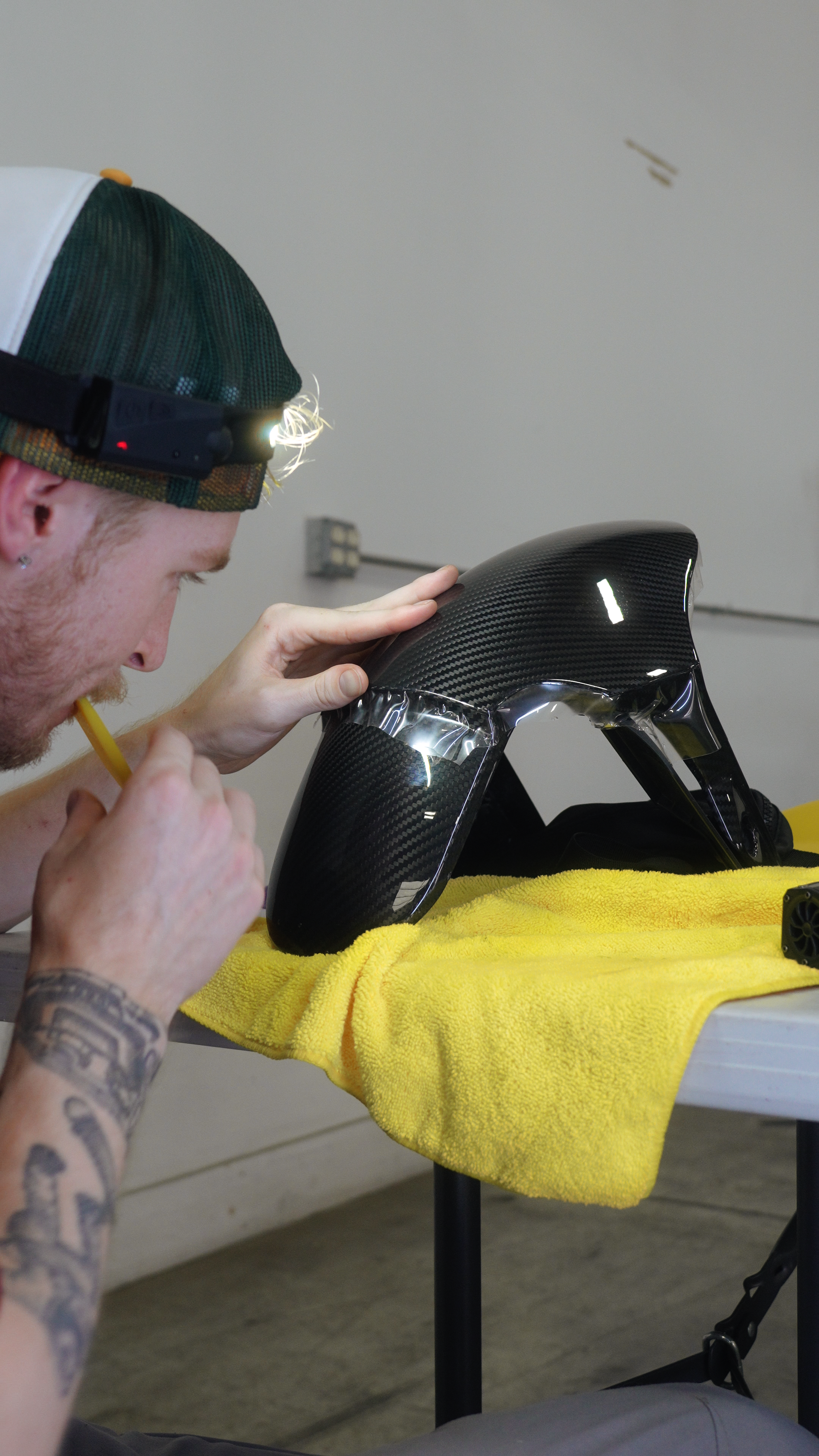 Man cleaning a black carbon fiber motorcycle fender with a toothbrush.