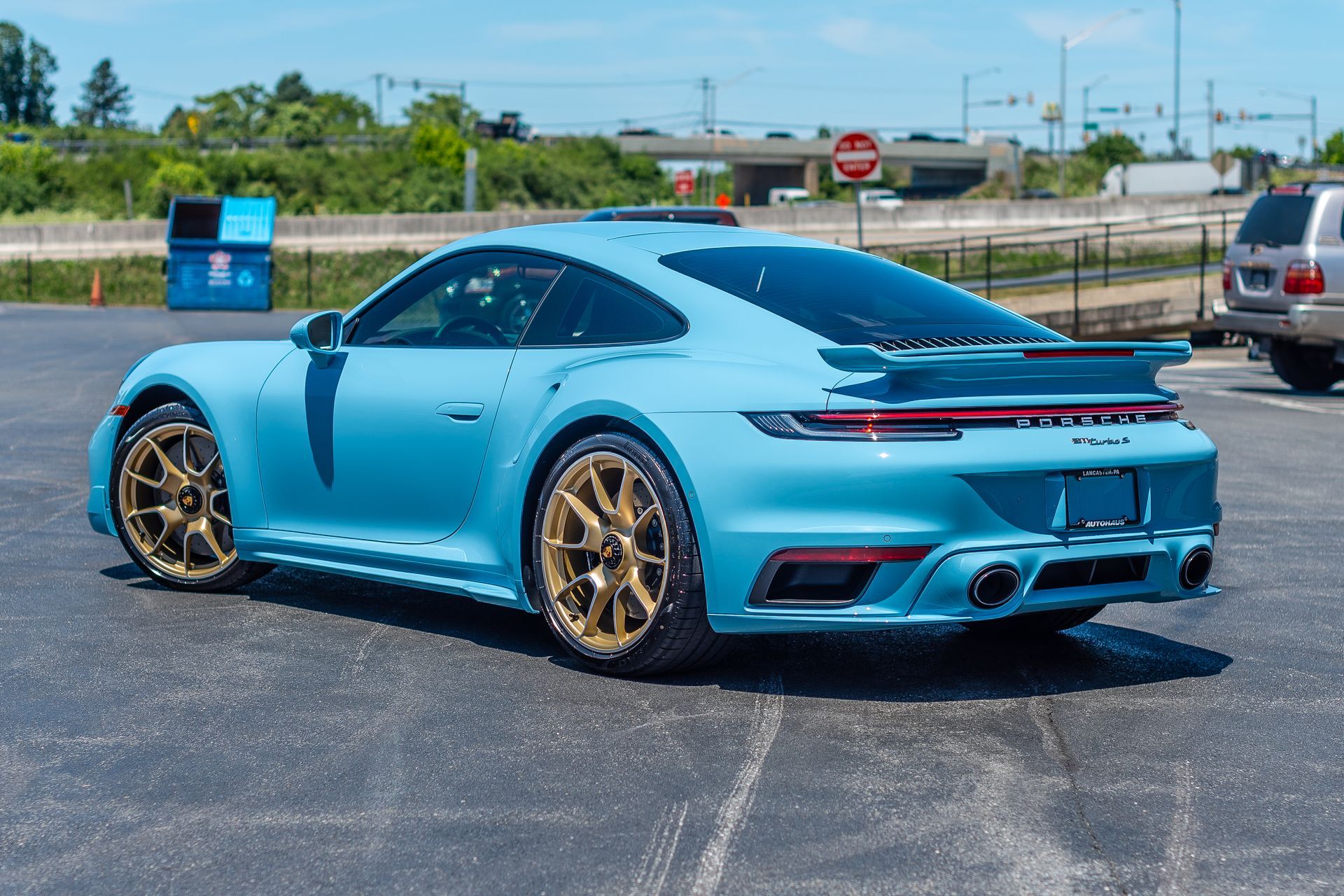 A blue porsche 911 turbo is parked in a parking lot.