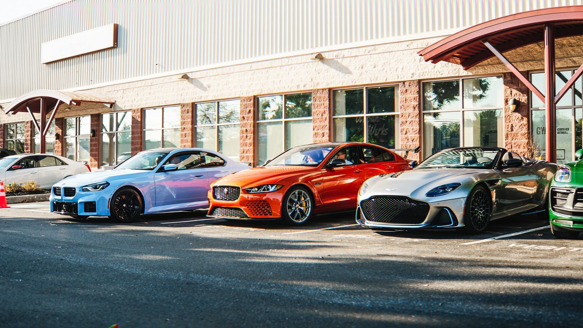 A row of cars are parked in front of a building.