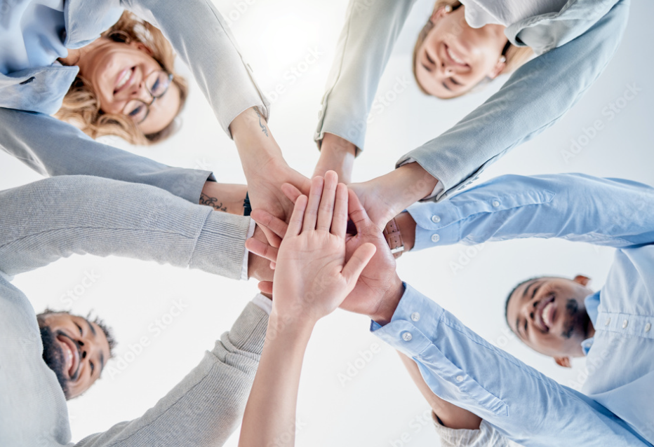 Smiling team ina circle, hands together, symbolising unity and expert recruitment in sales.