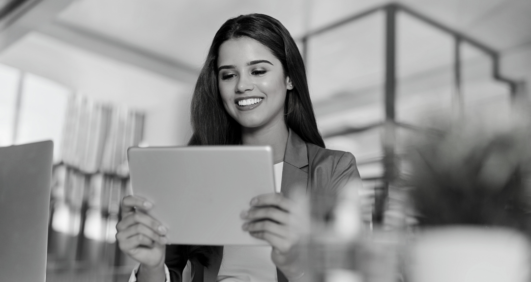 Woman smiling while looking at her iPad, strategising for sales in finance and fintech sectors.