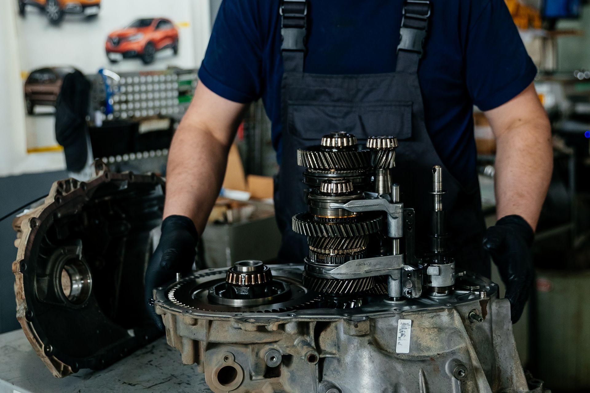 mechanic assembling or inspecting a disassembled car transmission on a workbench.