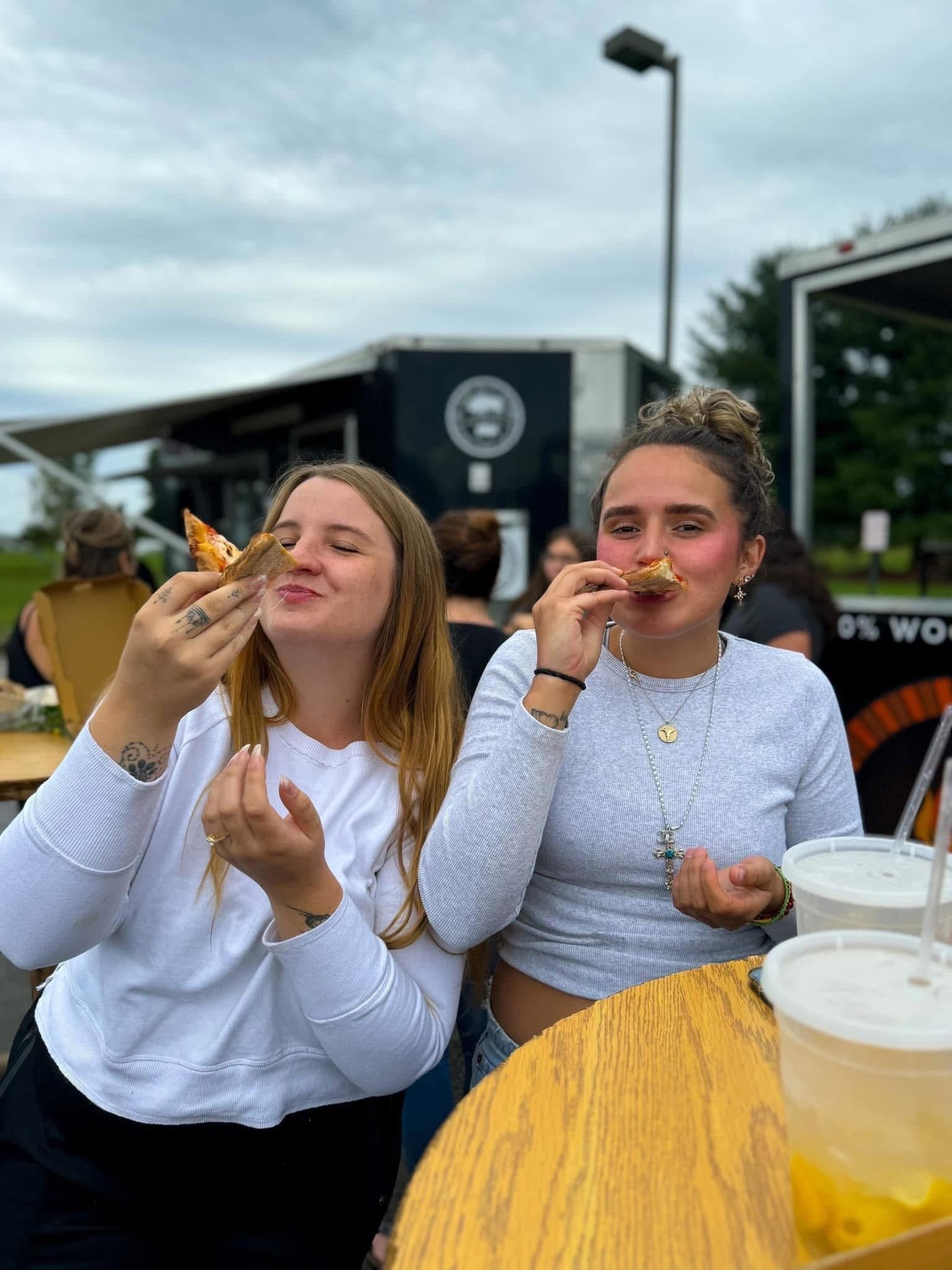 two women eating pizza at event