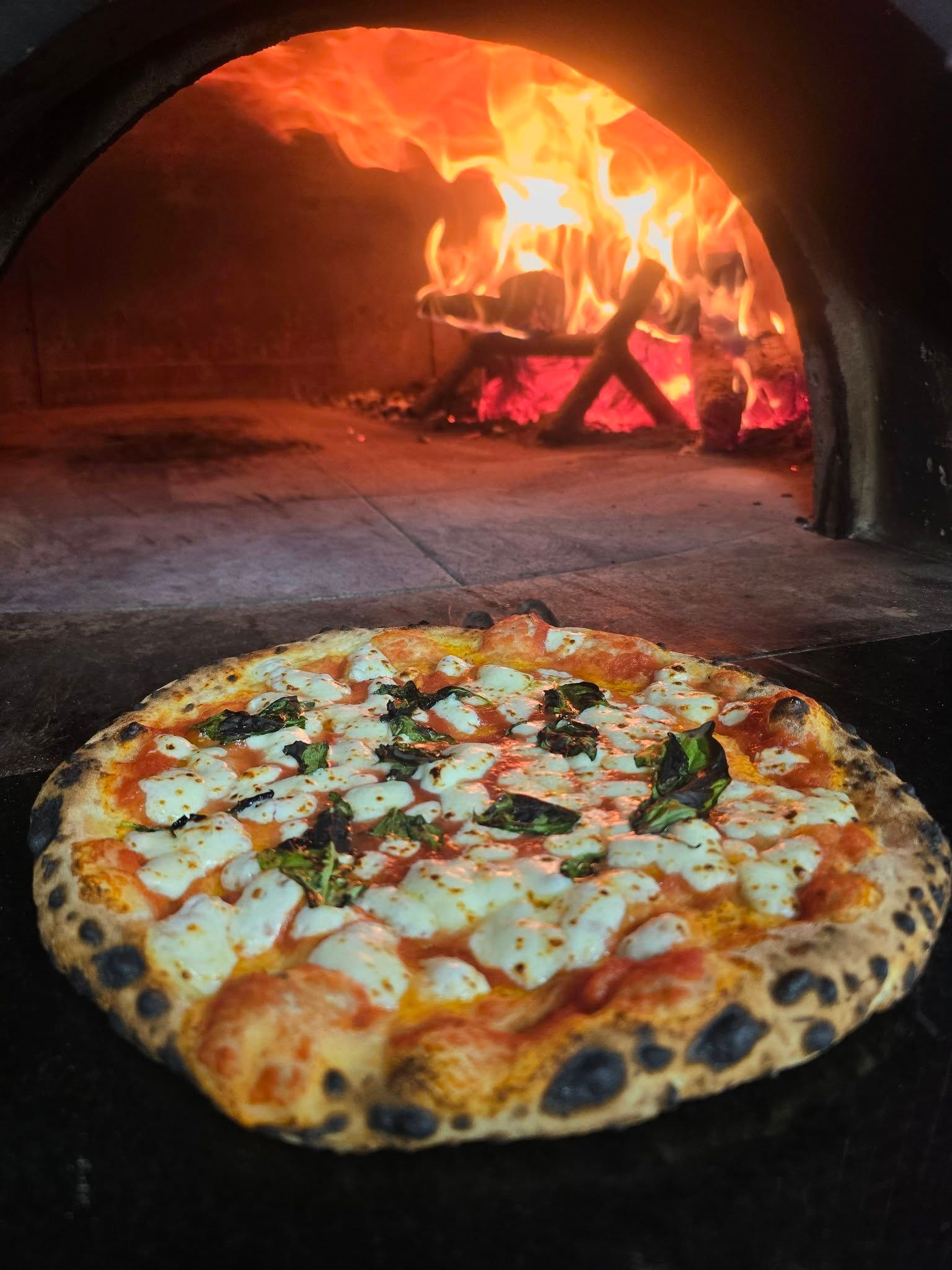 Neapolitan pizza coming out of pizza oven