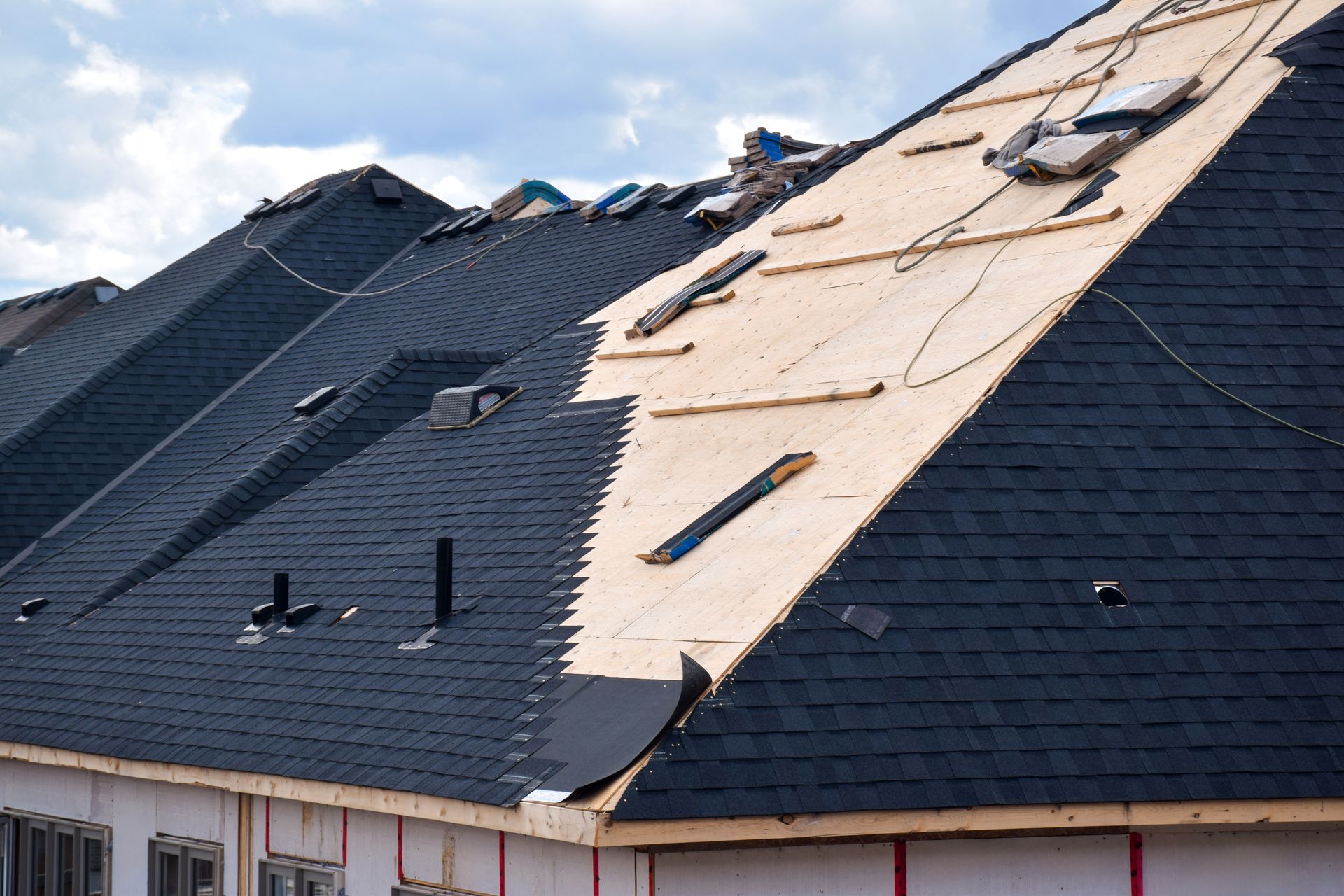 Damaged roof with missing shingles and exposed underlayment after storm damage