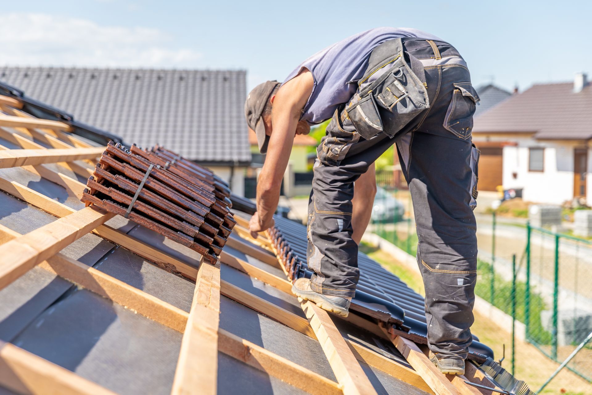 Worker installing roof tiles on a house roof in bright daylight