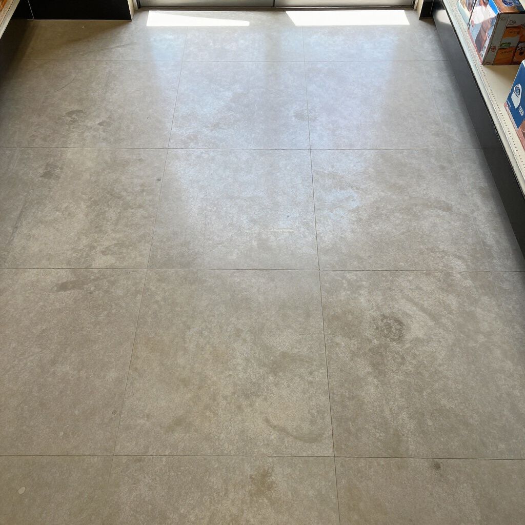 A view of a floor made of large, light-grey, mottled square tiles in an indoor retail space.
