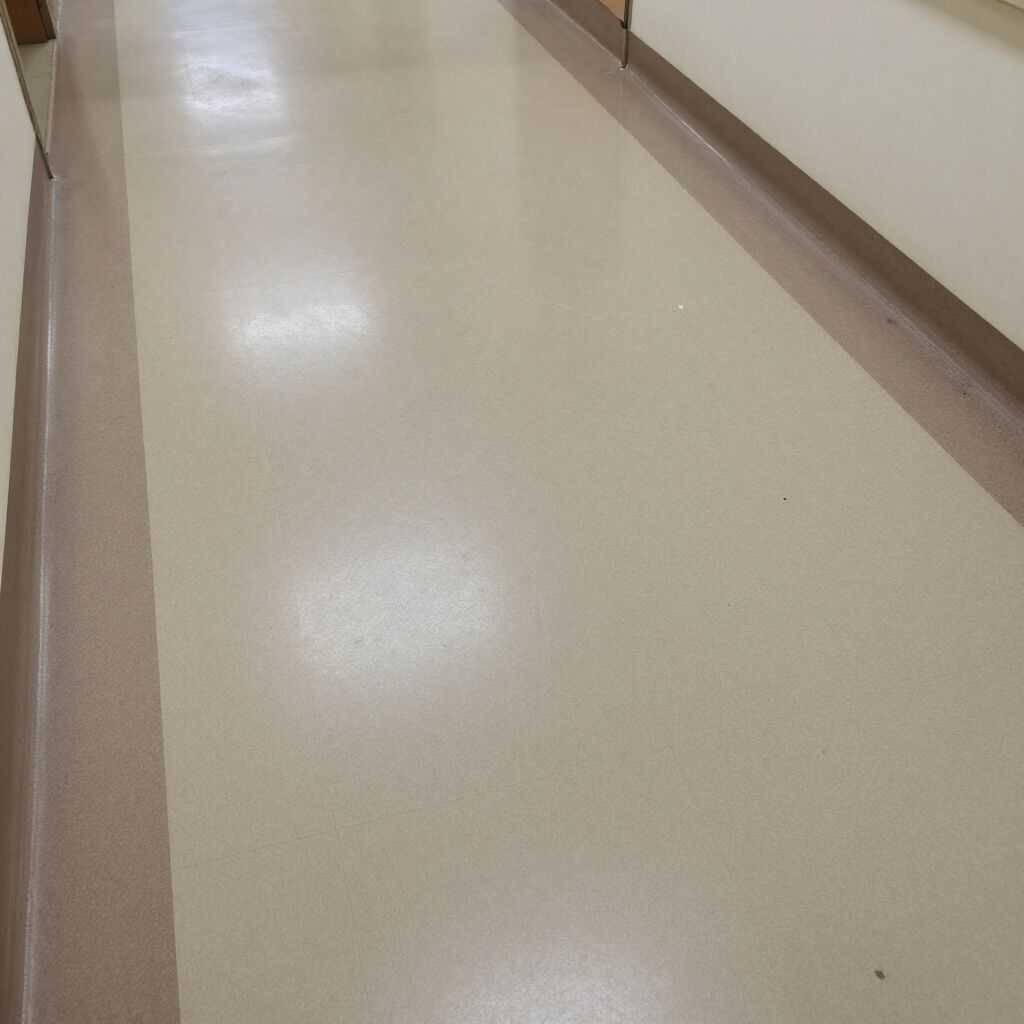 A beige-floored hallway with brown trim along the walls, illuminated by bright overhead lighting.