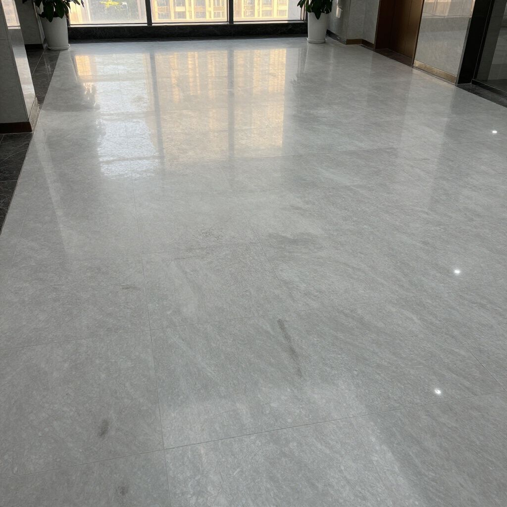 A wide, polished gray marble floor reflects sunlight from large floor-to-ceiling windows in a bright, modern hallway.