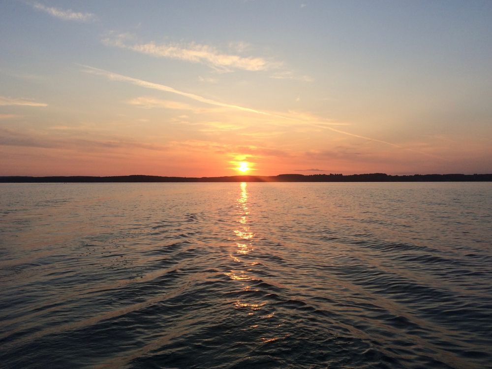 Sunset over calm water with orange sky and a bright reflection on the horizon