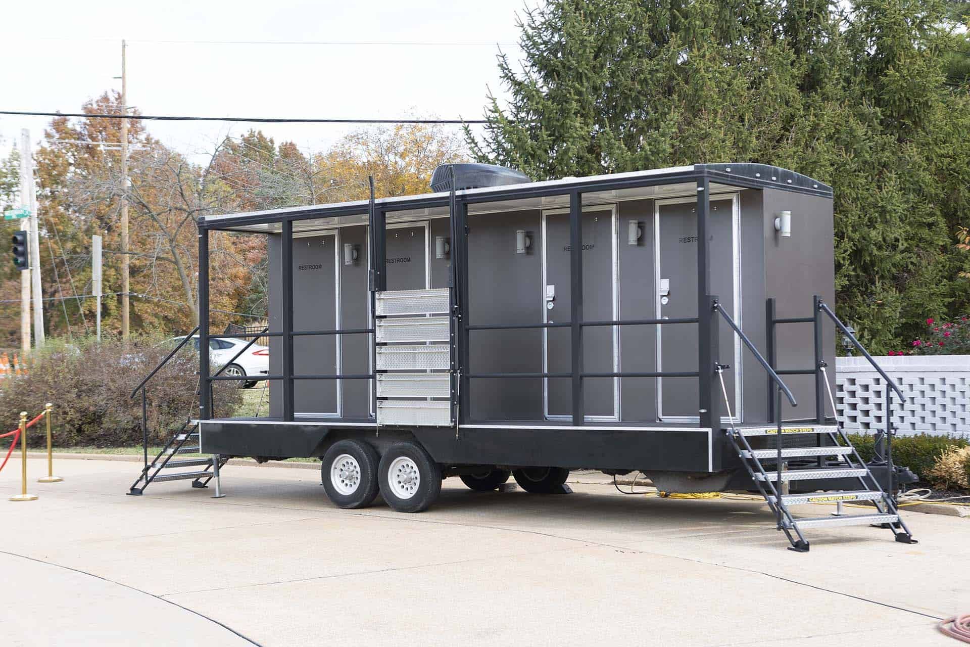 Gray mobile trailer with ramps parked outdoors on a concrete lot