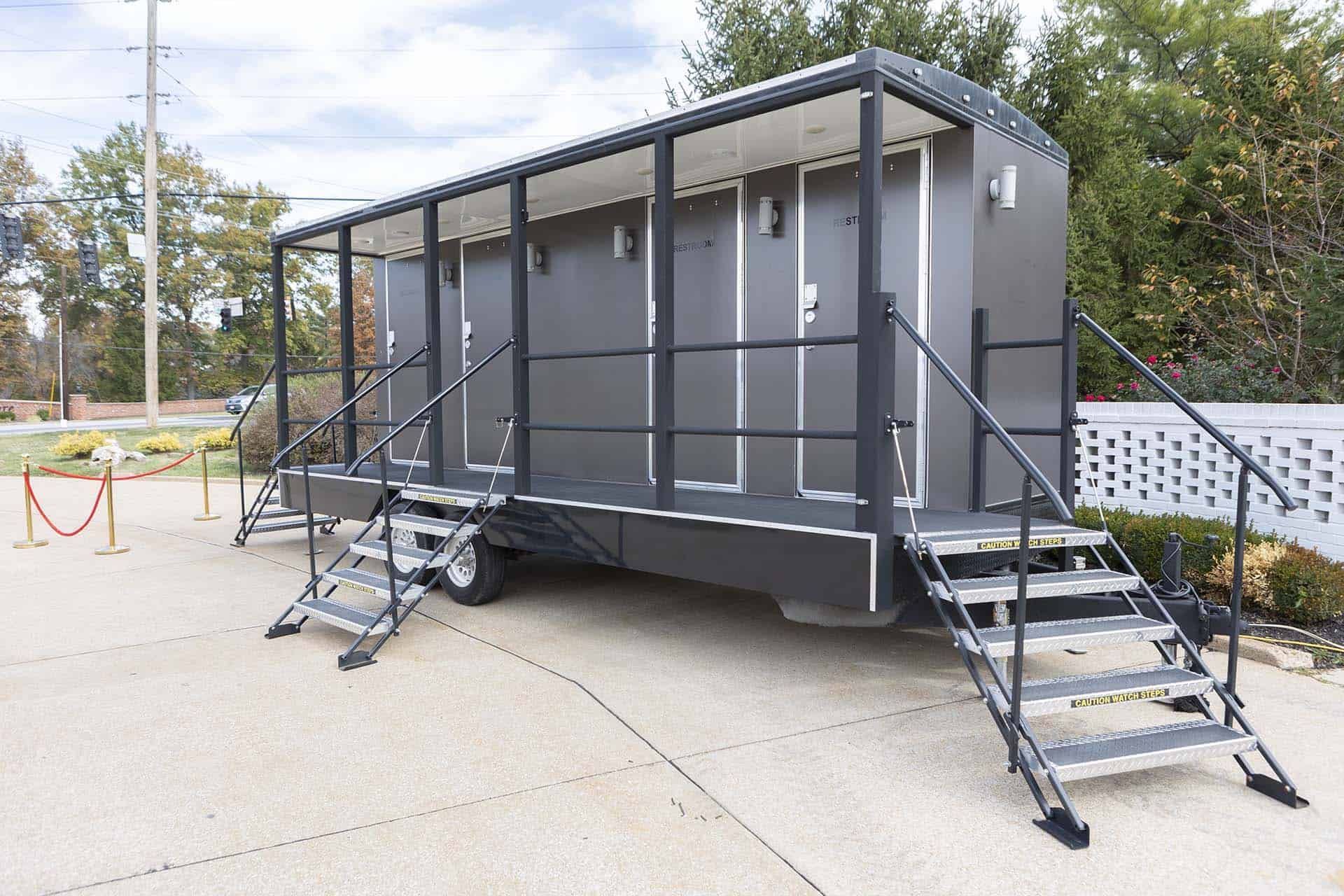 Gray portable trailer with stairs on both ends in an outdoor parking lot