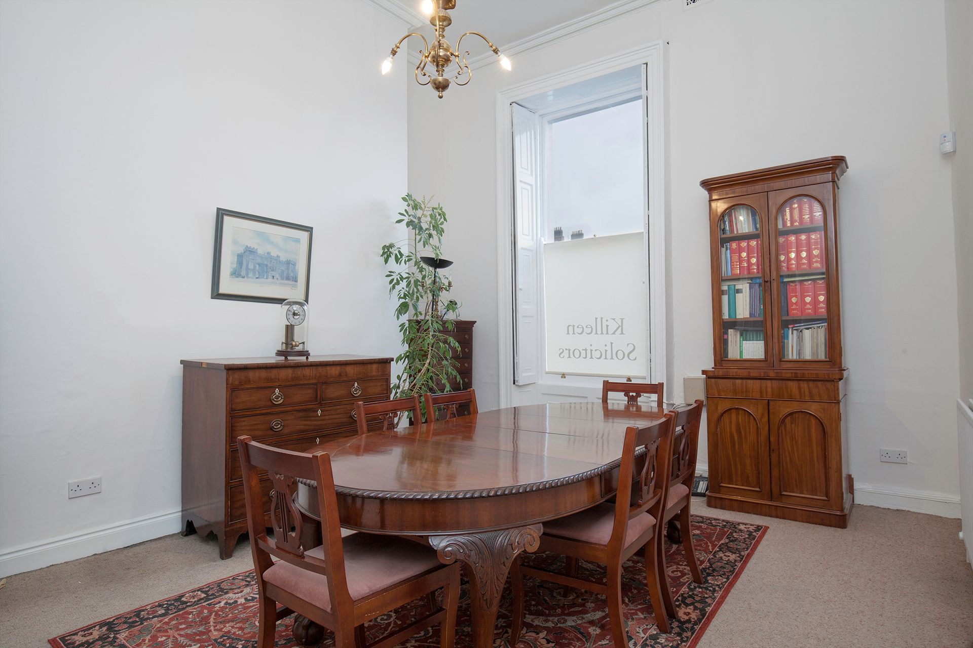 Dining room with wooden table, chairs, cabinet, and sideboard in a bright corner by a door.