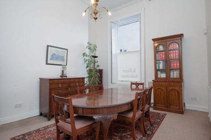 Dining room with wooden table, chairs, cabinet, and sideboard in a bright corner by a door.