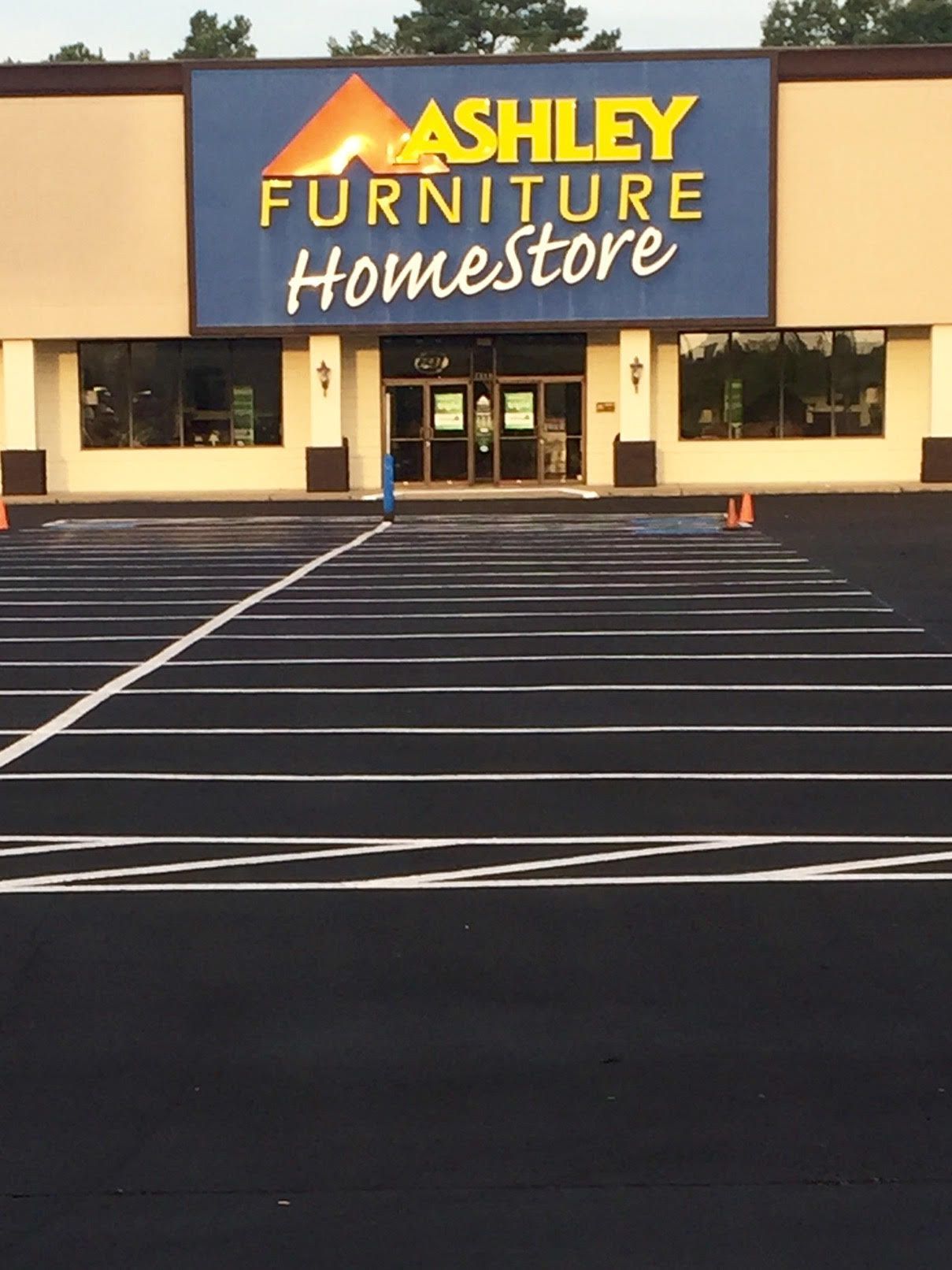 Ashley Furniture Homestore storefront with a mostly empty parking lot at sunset