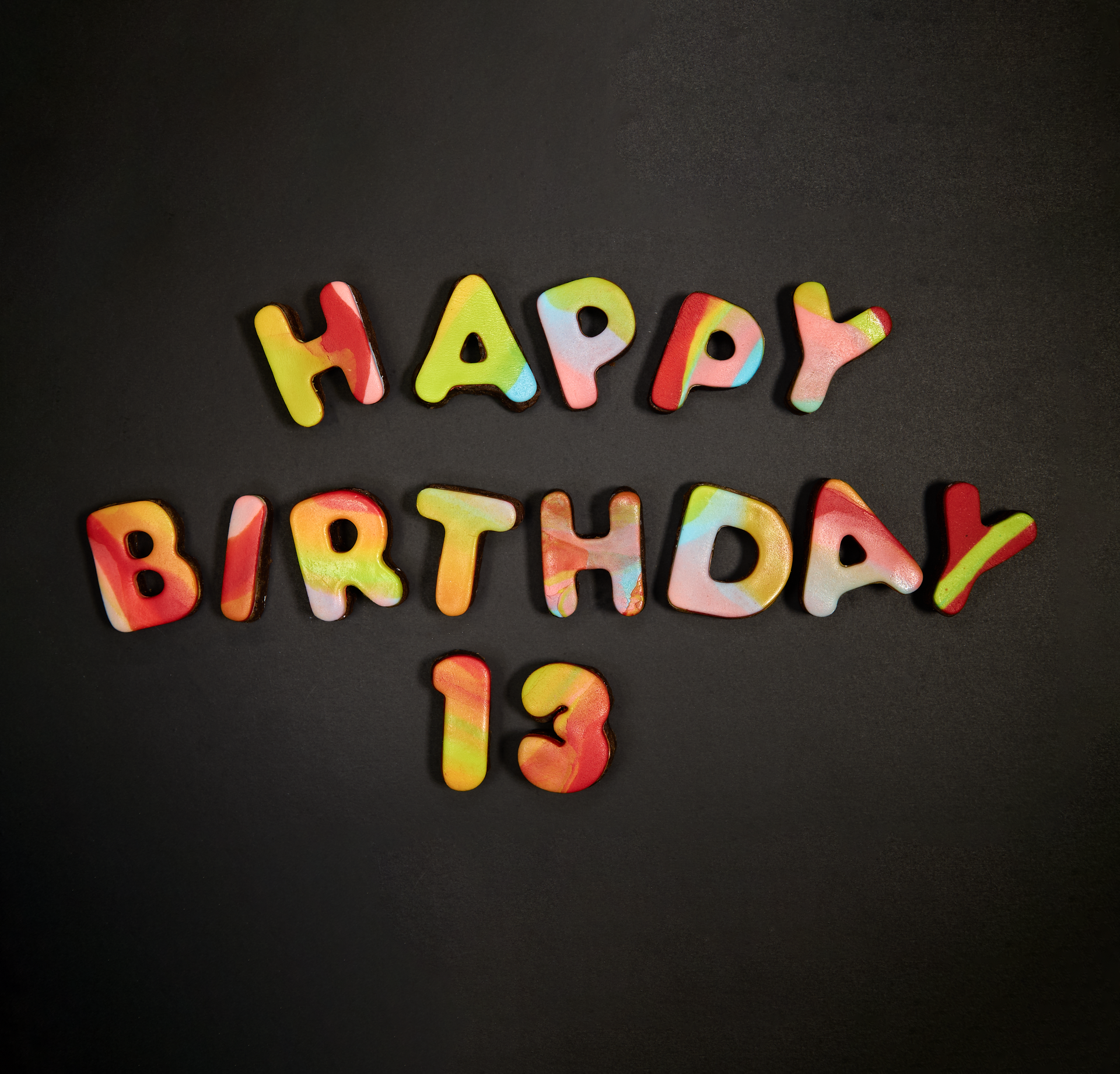 Colorful letters spell out happy birthday 13 on a black background