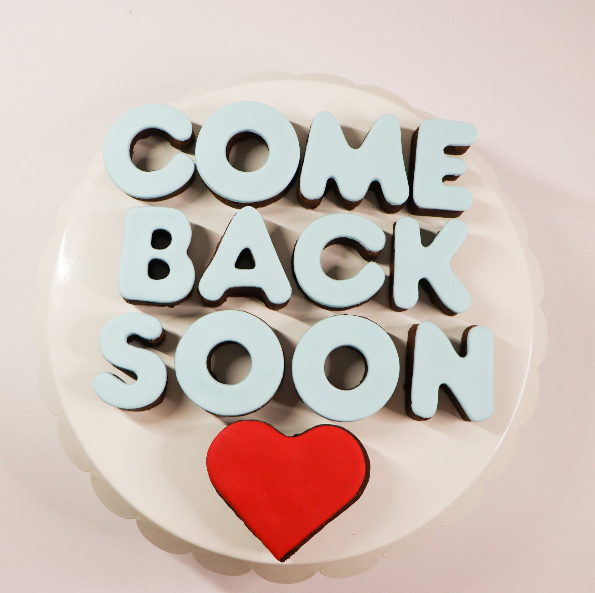 A white plate with the words come back soon on it