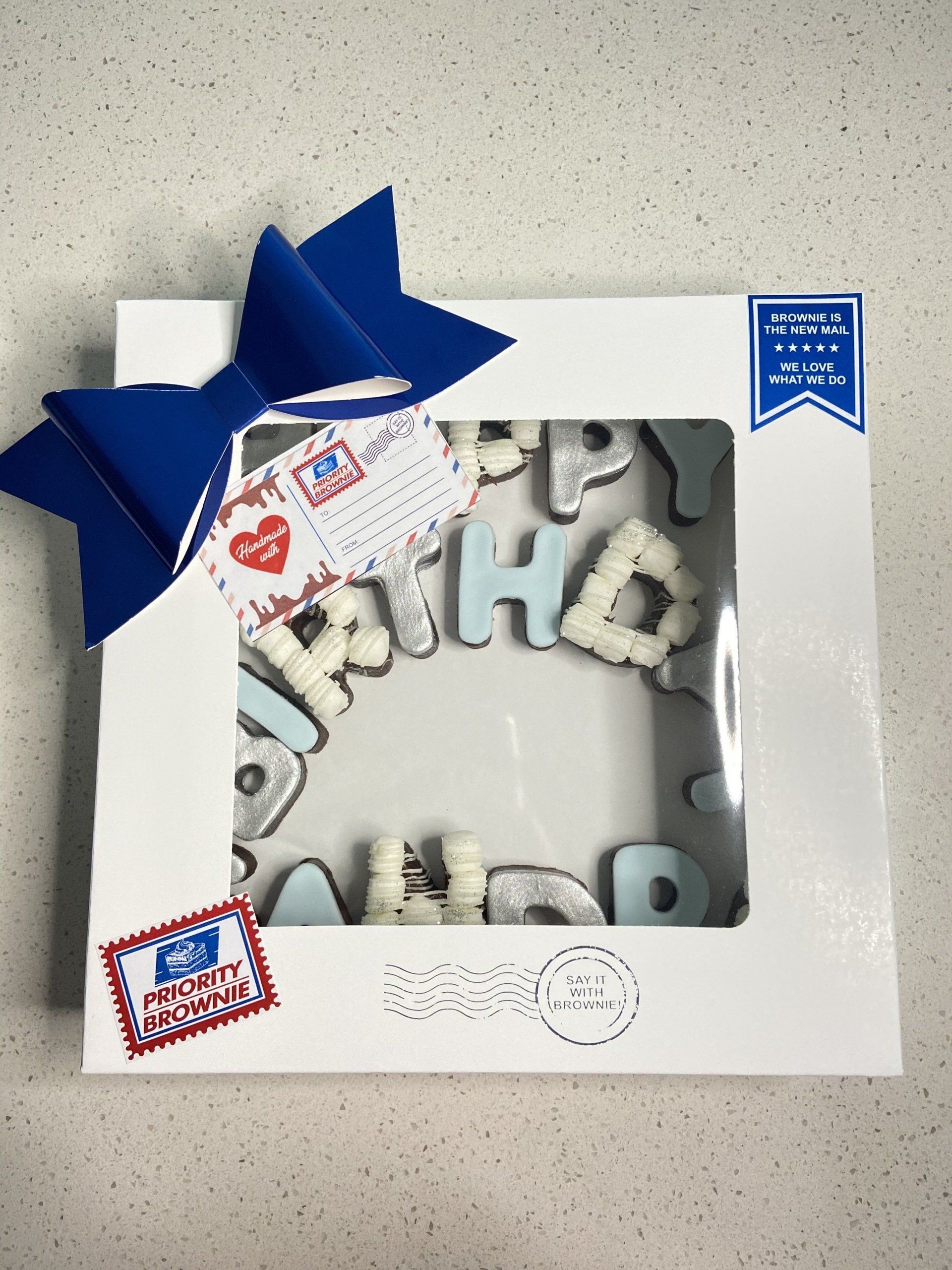 A white box with a blue bow and letters that say happy birthday